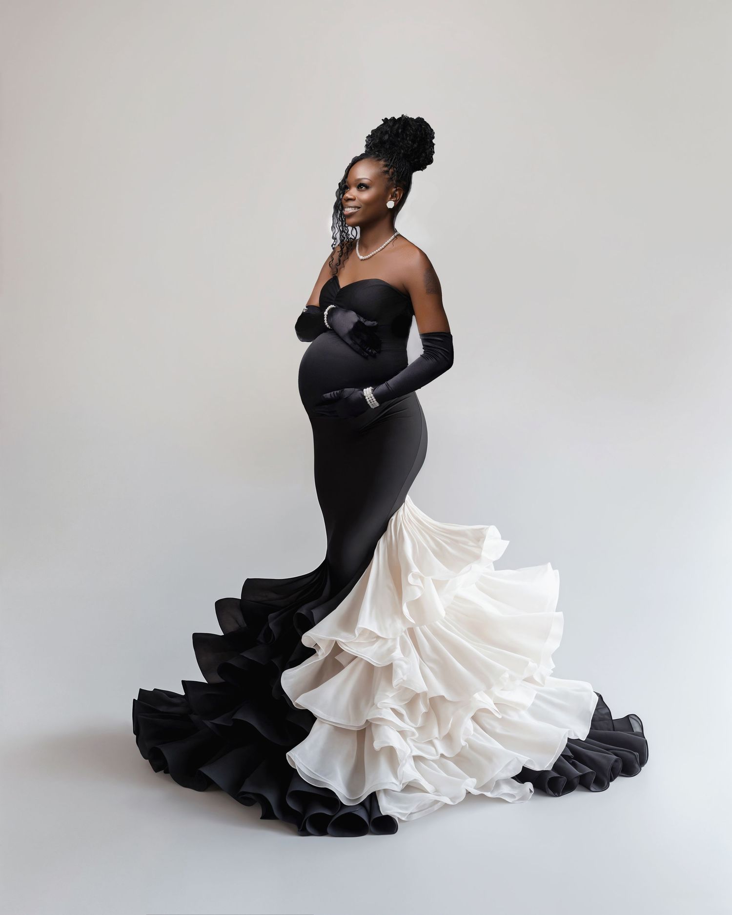 A dramatic fashion photo series showing a model in a black and white mermaid gown posing gracefully against a white backdrop.