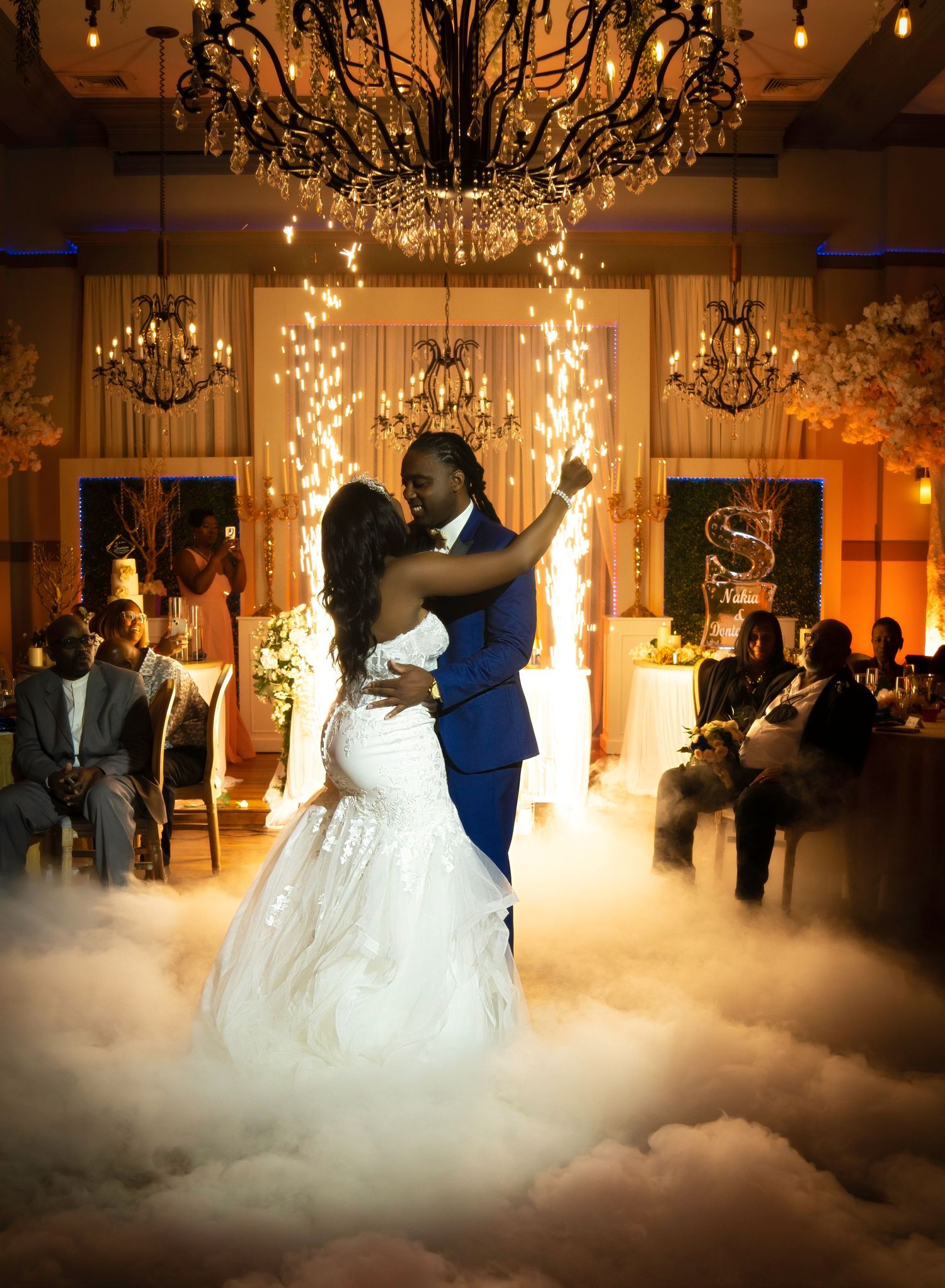A romantic first dance at a wedding reception with fog effects and elegant chandeliers creating a dreamy atmosphere.