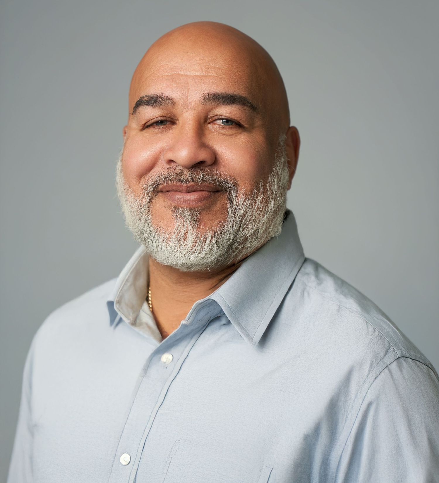Series of professional portraits showing a man in a light gray button-down shirt with a gray beard.