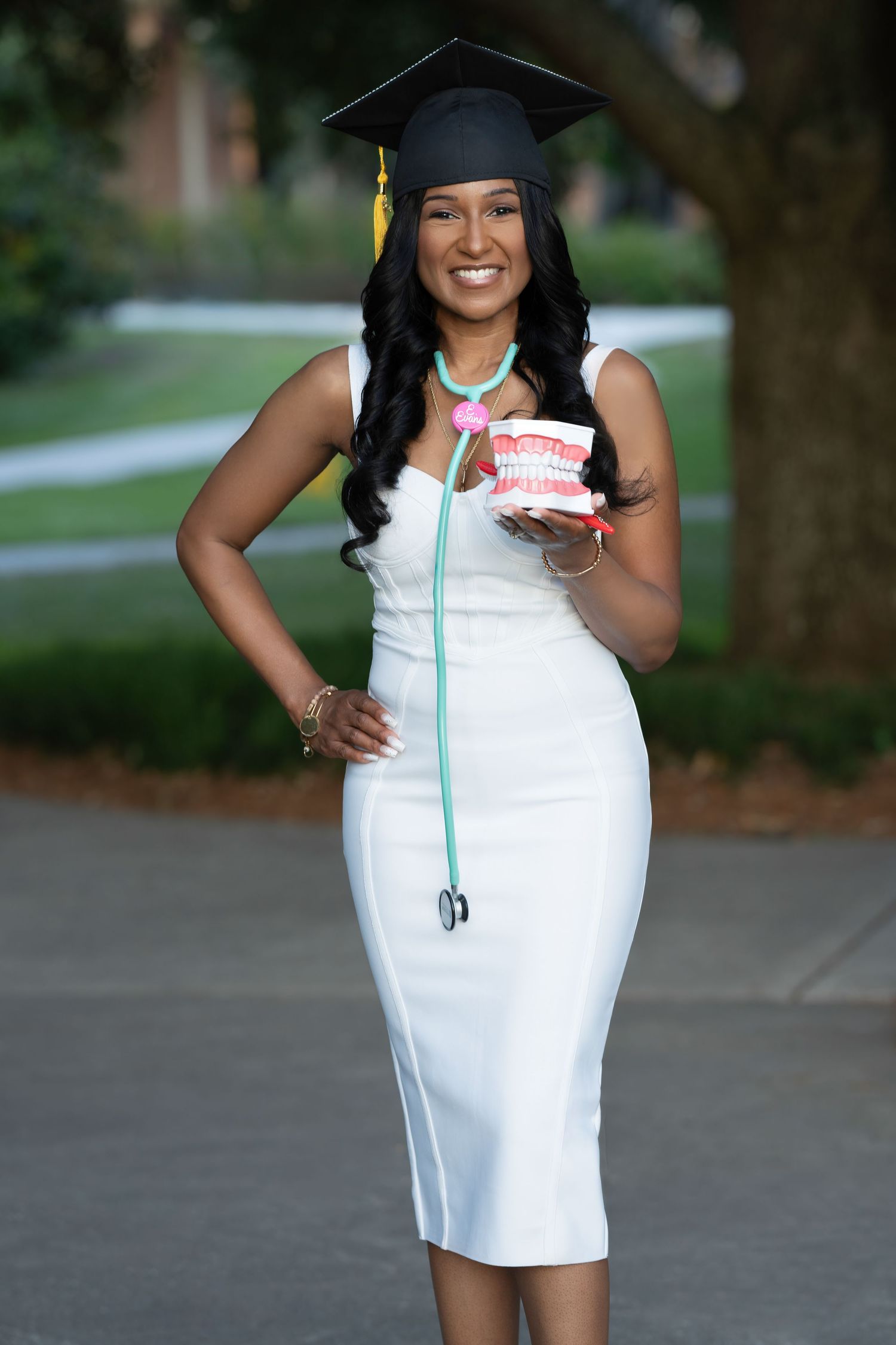 Graduation photos in white dress and cap against campus backdrop outdoors.