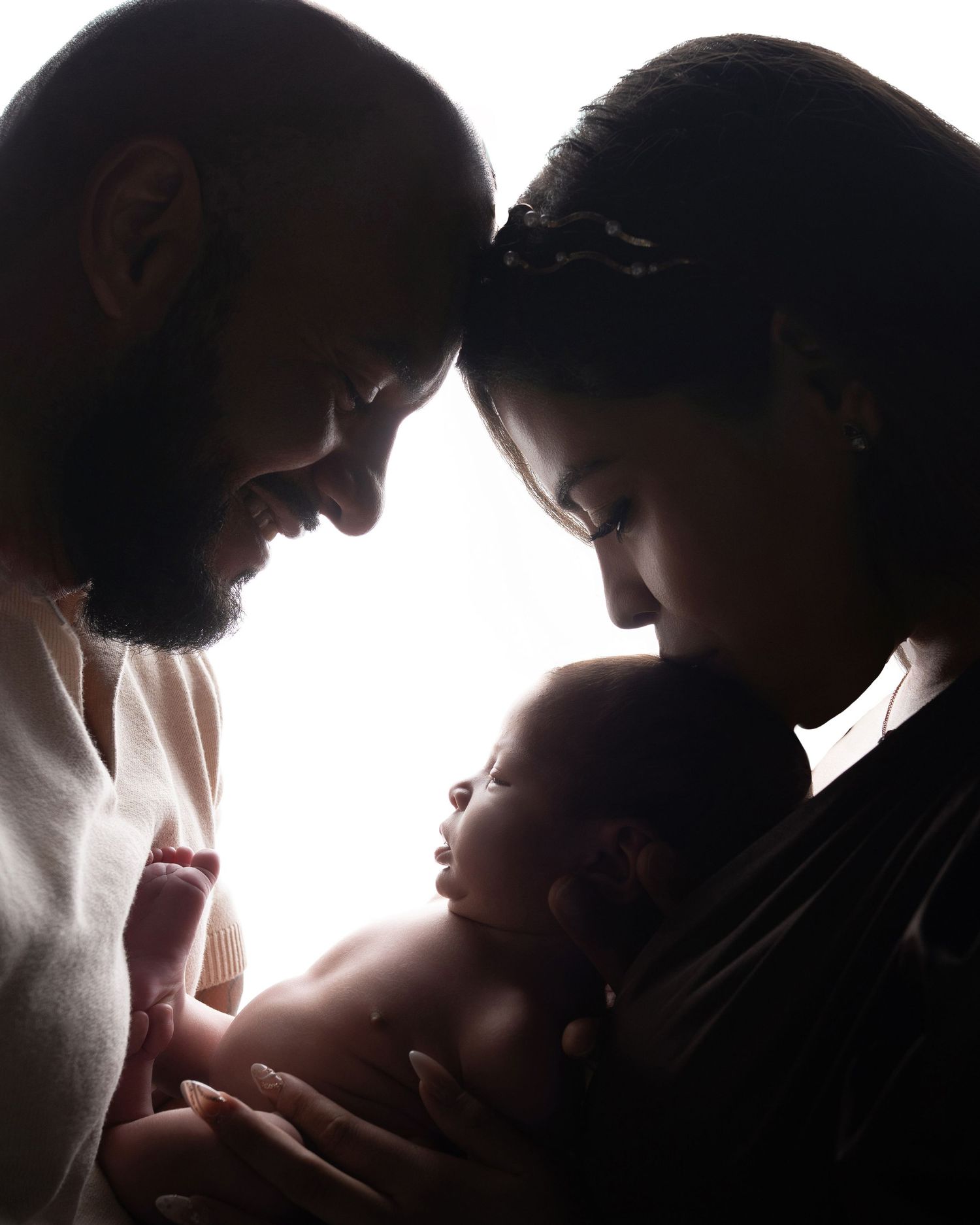 A silhouetted family shares an intimate moment together against a bright white background.