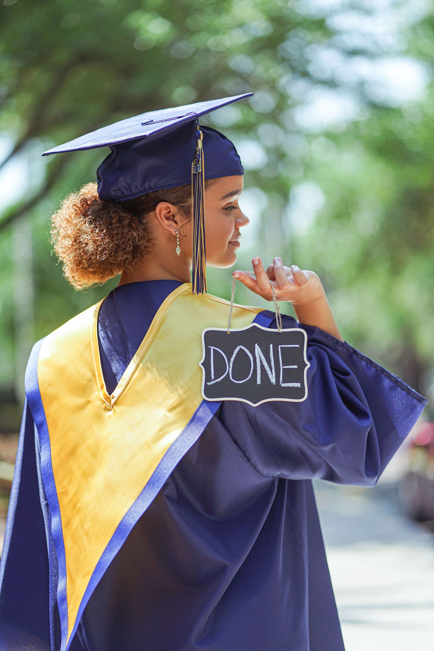 Graduate in navy and gold graduation gown with 'DONE' written on cap.