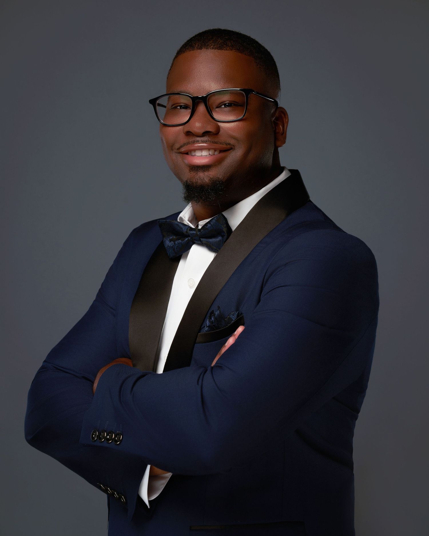 Professional portraits of a person in a navy suit and white shirt against dark background.