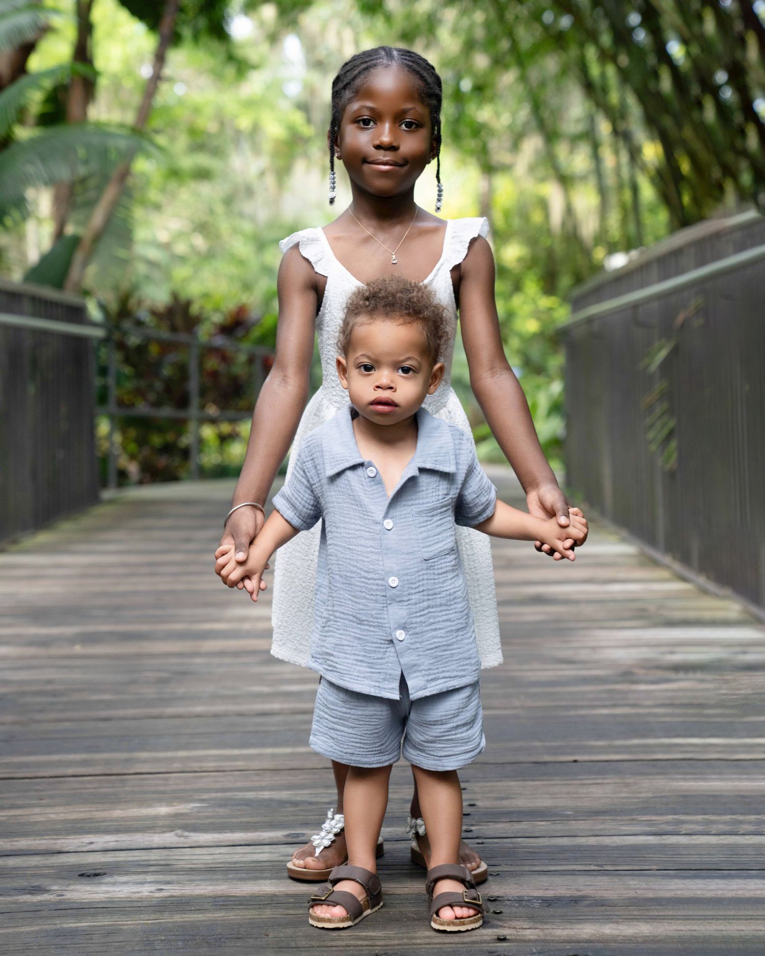 Two children holding hands outdoors on a bridge
