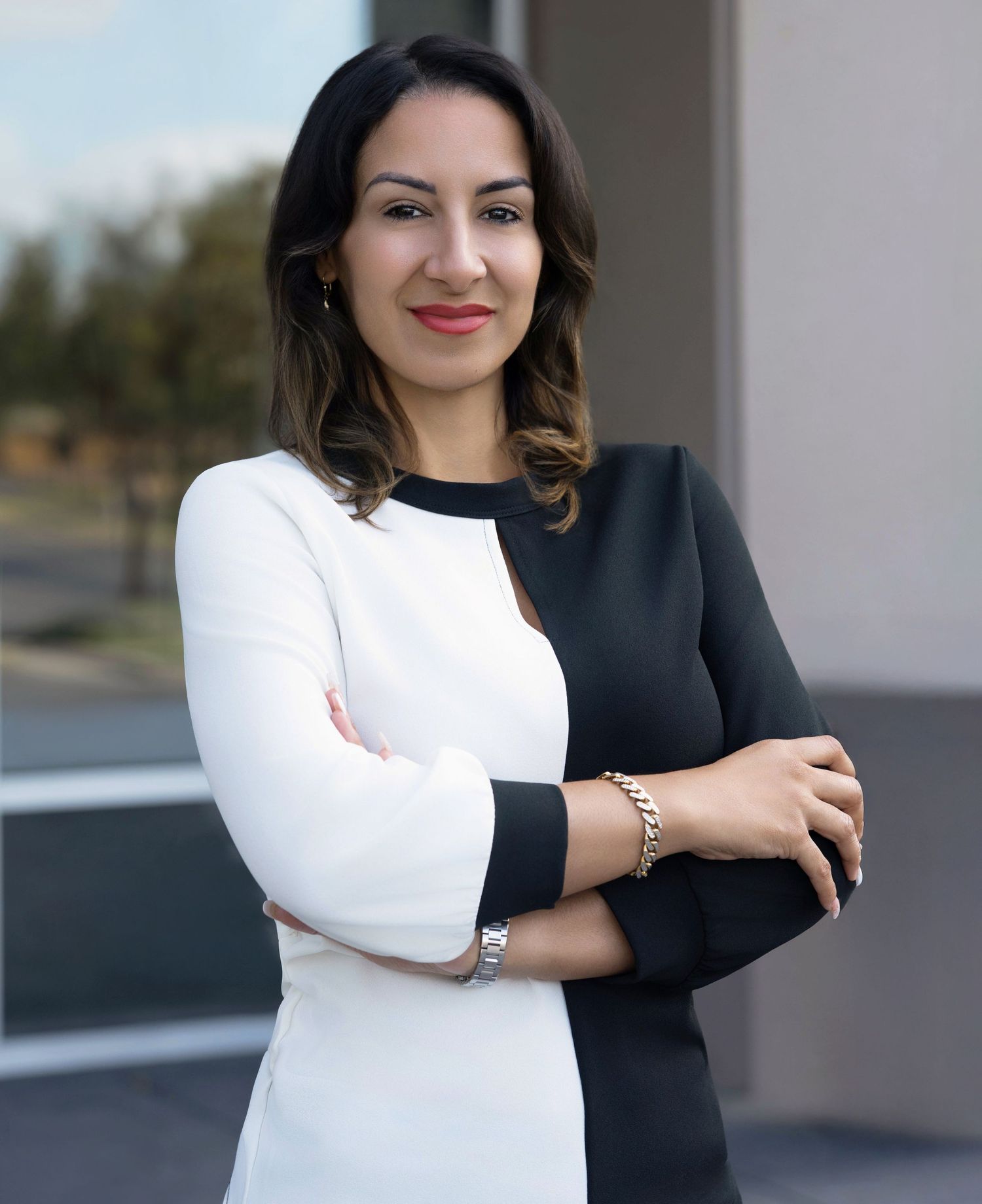 Professional portrait of someone in a black and white color block dress with crossed arms and a confident smile.