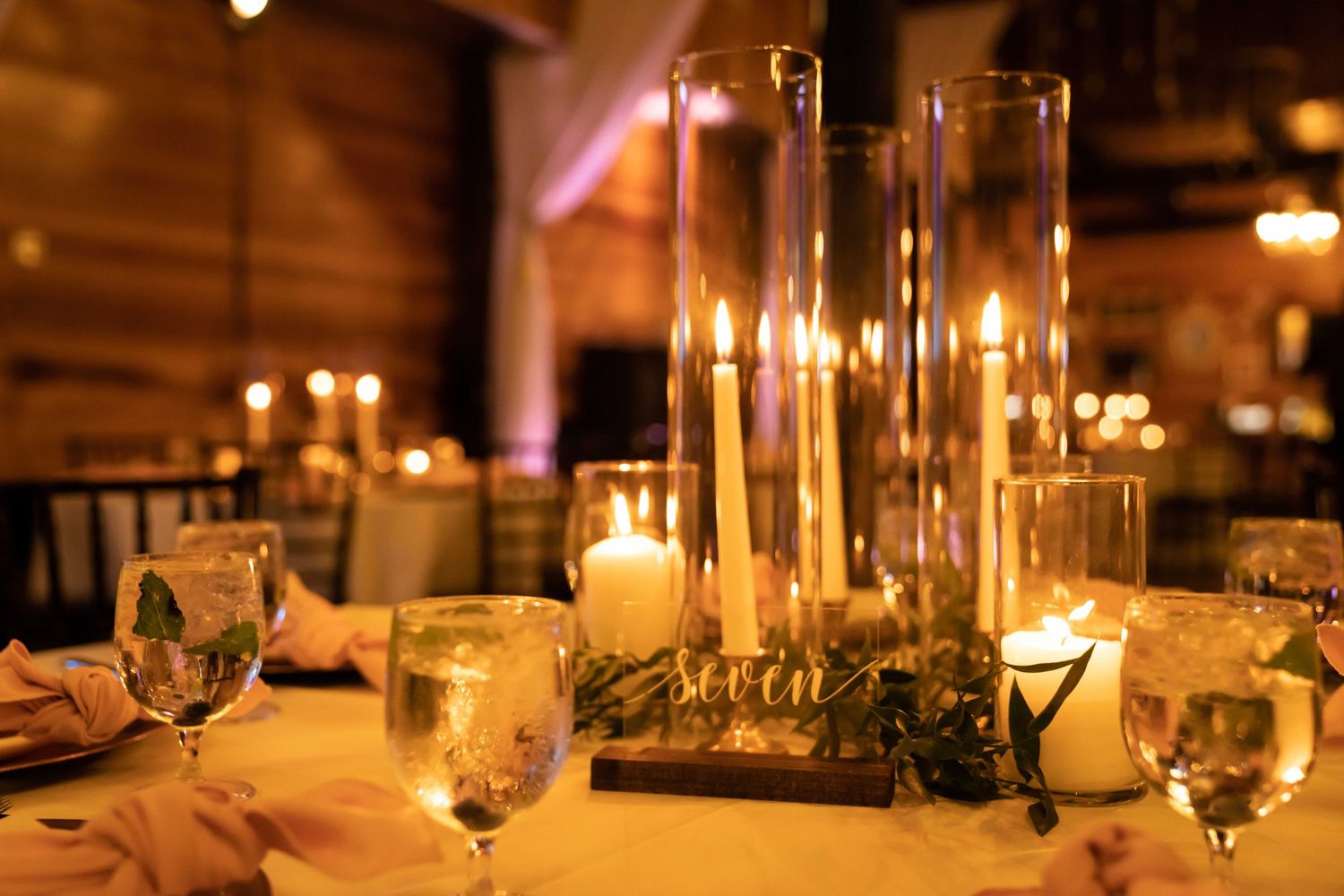 Elegant candlelit table settings with wine glasses and soft lighting create a romantic dining atmosphere.