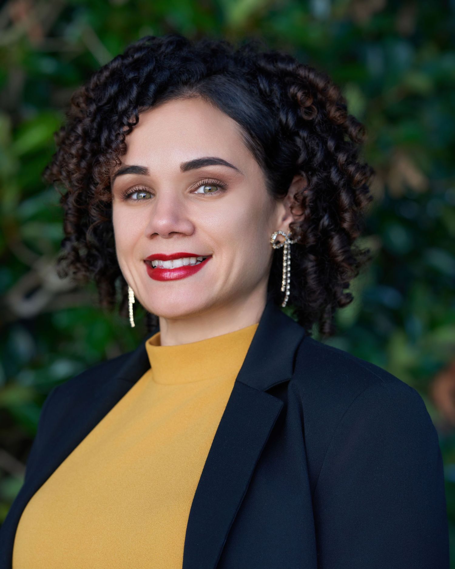 Professional portraits featuring a woman in a bright yellow top and black blazer against natural background.