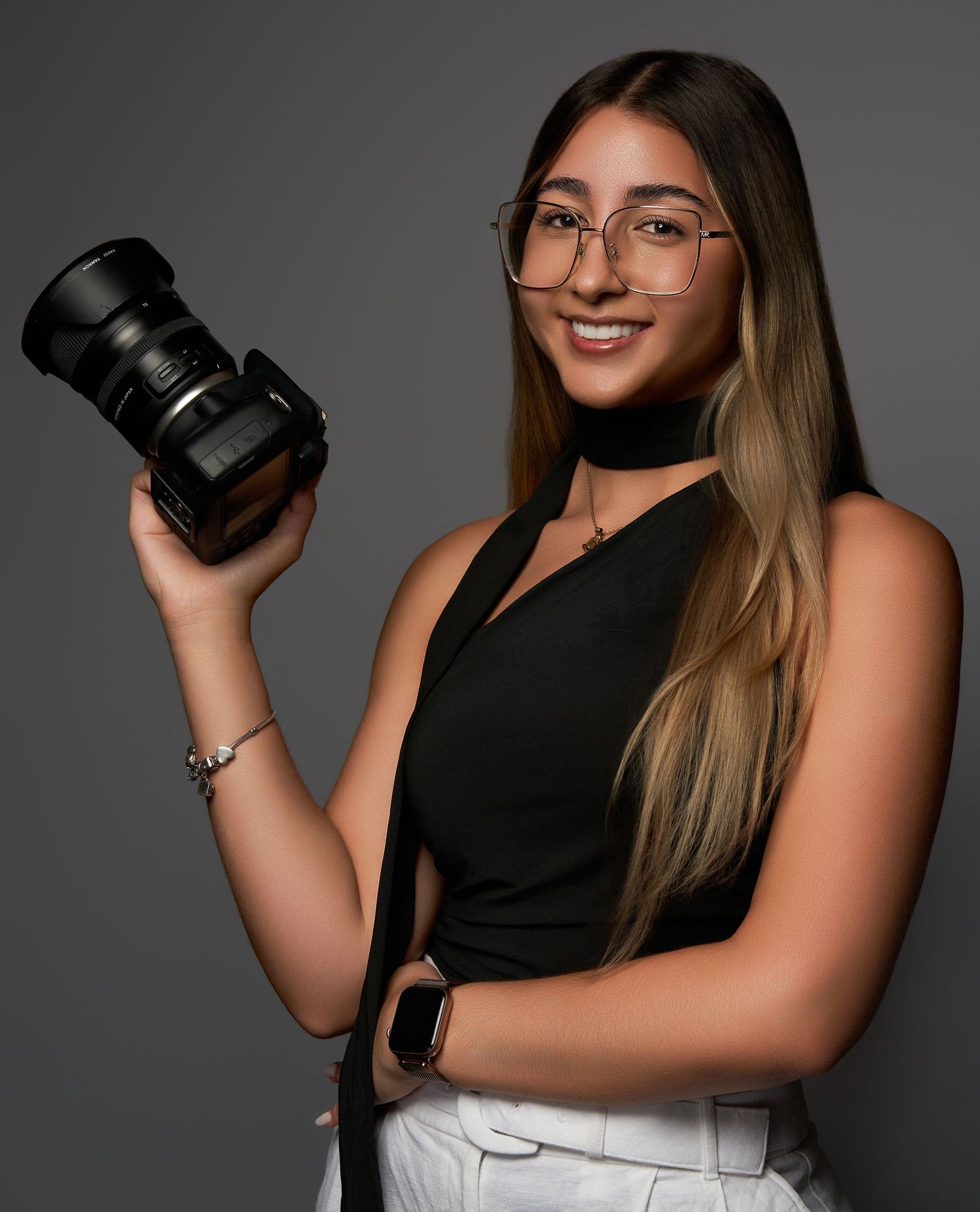 Portrait series of photographer holding camera lens against gray backdrop.