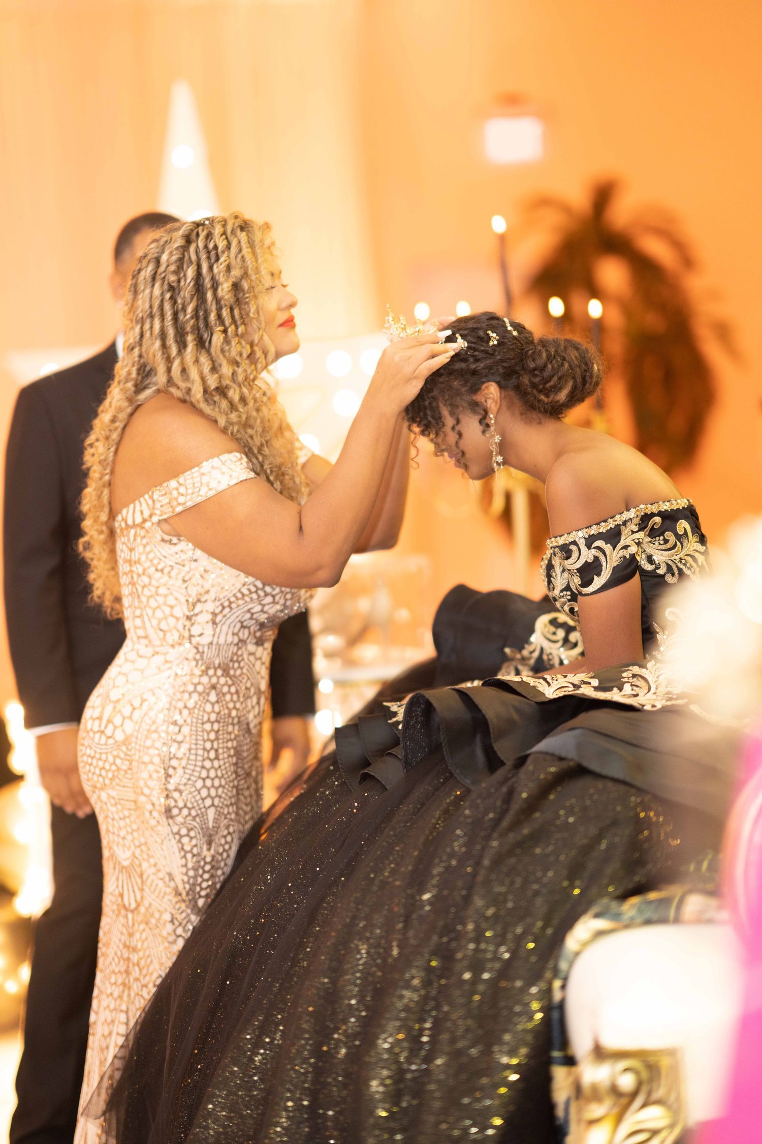 Elegant party scene with guests in formal attire dancing under warm orange lighting.