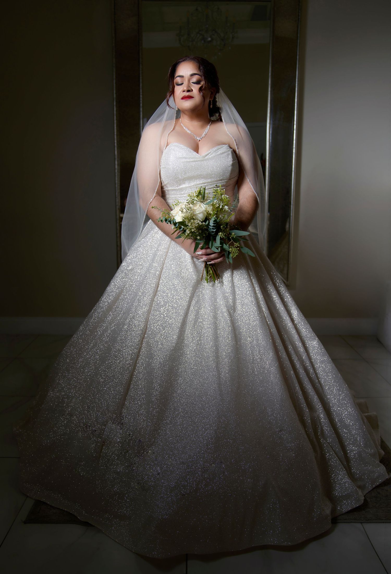 Elegant sparkly white ball gown wedding dress photographed in dramatic lighting.