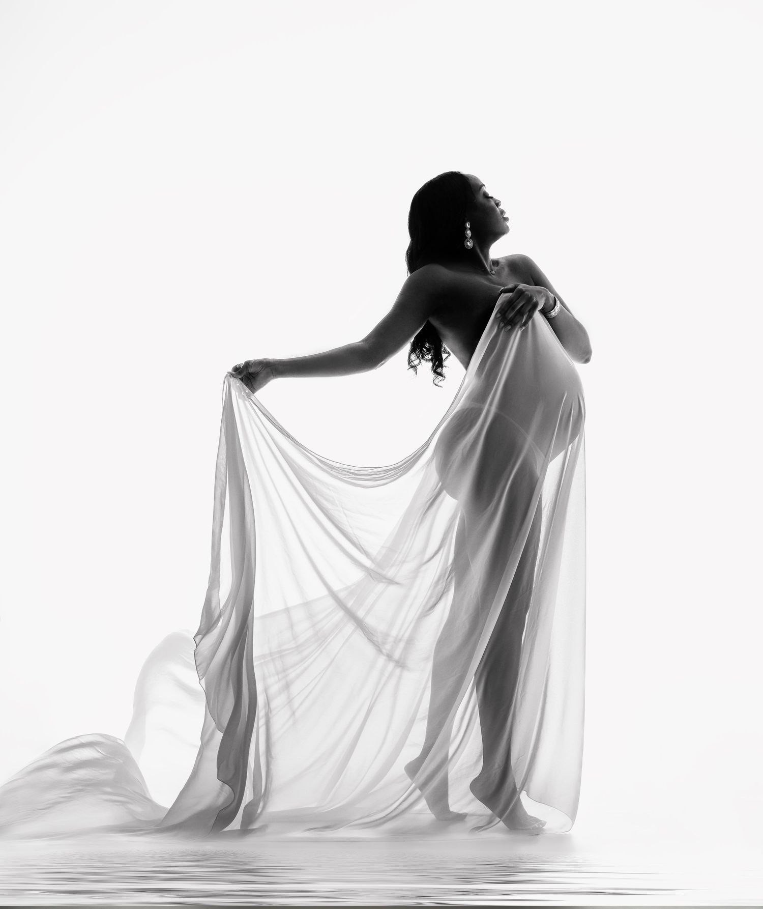 Artistic black and white silhouette of a figure draped in flowing white fabric.