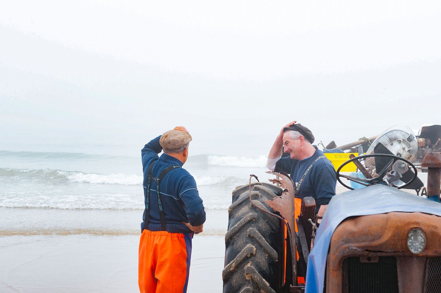 Norfolk crab fishermen taliking as they bring their boat out of the sea at Cromer. Classic Norfolk 
Photograph by Danny Elwes