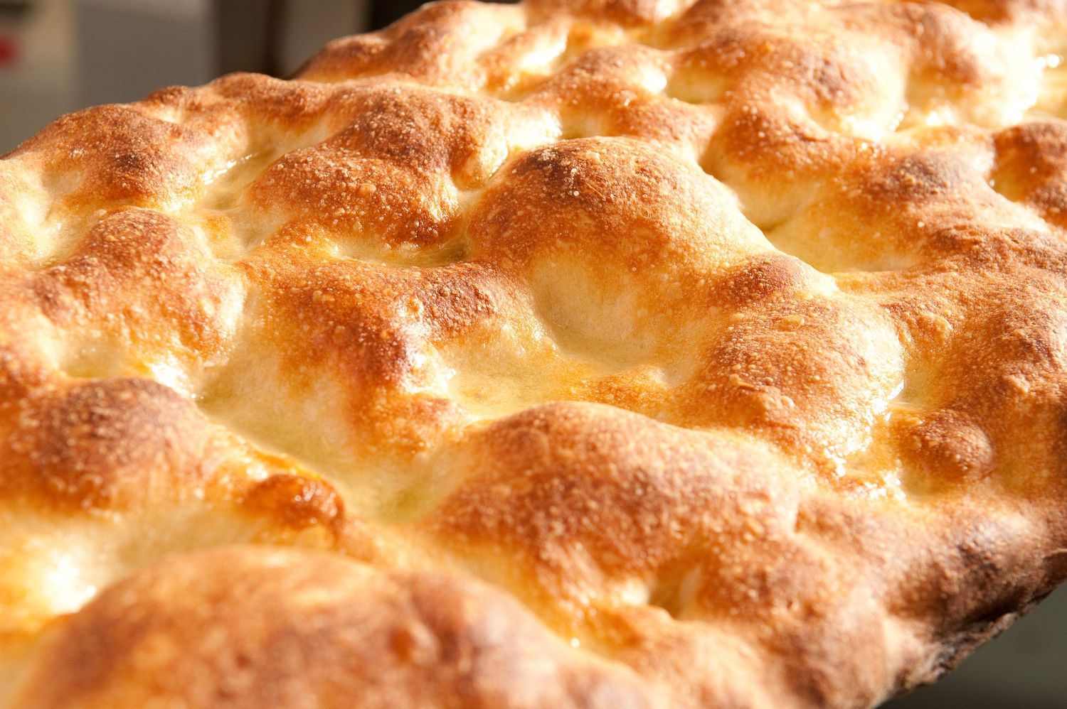 Golden-brown focaccia bread with a crispy, dimpled crust fresh from the oven.