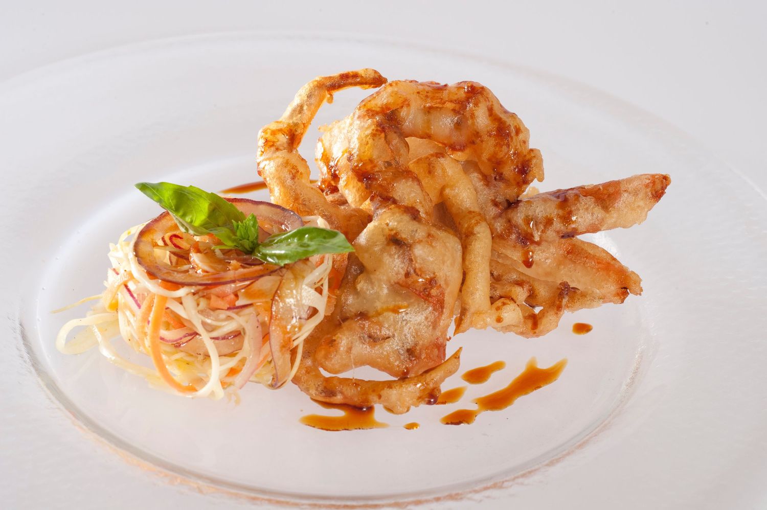 Gourmet shrimp dish with pasta, fresh basil, and savory sauce on a white plate.