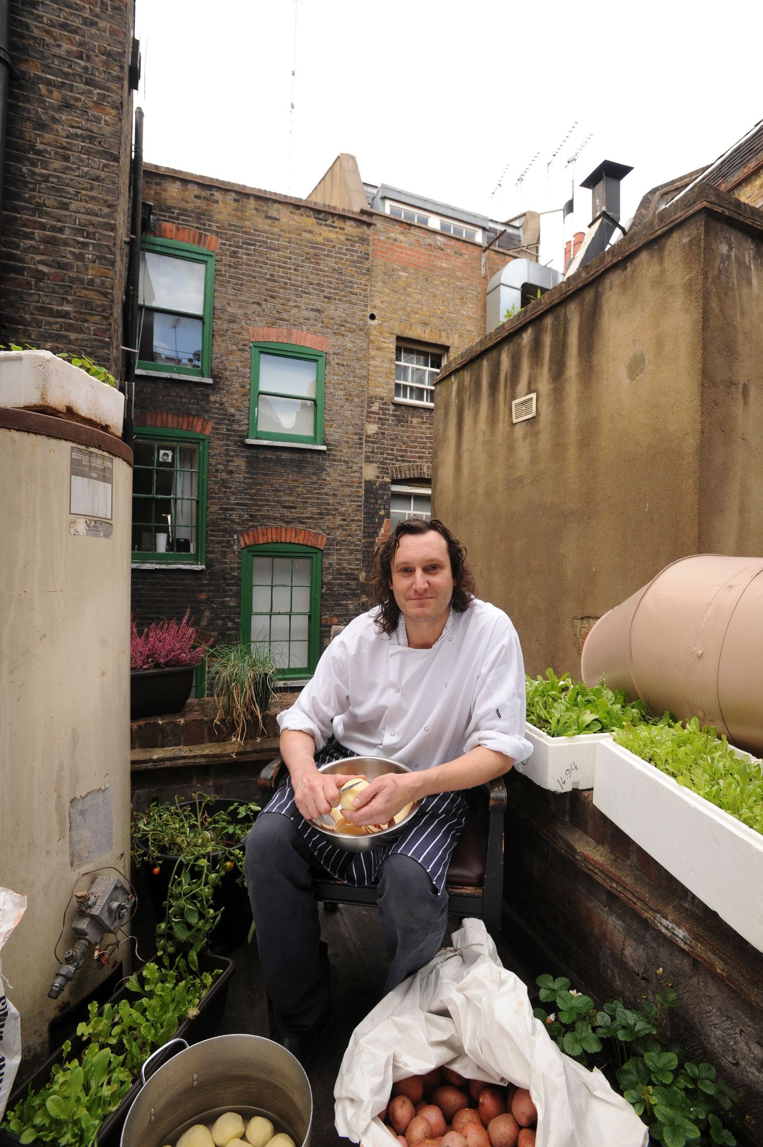 Head Chef Andy Campbell at 23 Romilly Street, Soho. Peeling potatoes for service, on the little balcony.
Photograph by Danny Elwes