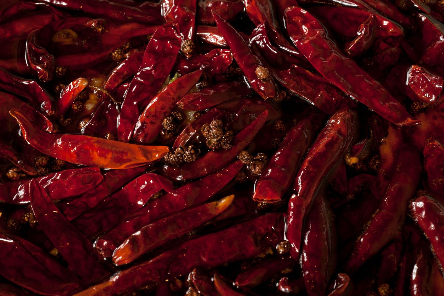 Close-up of dried red chili peppers piled together, showing deep crimson color and wrinkled texture.