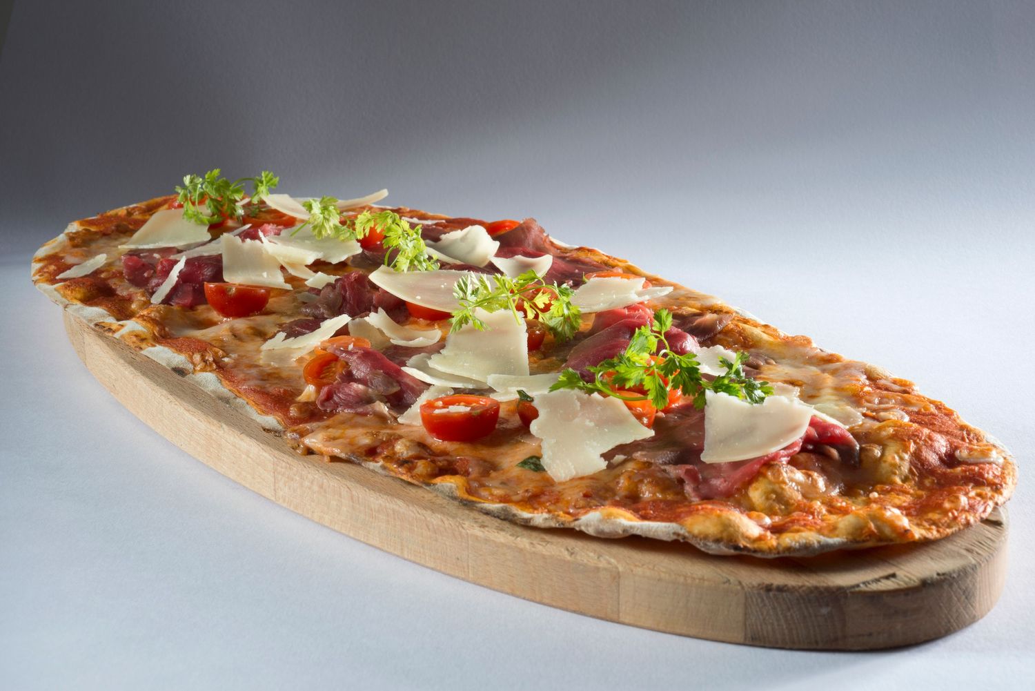 Gourmet flatbread pizza topped with fresh ingredients on wooden serving board for Brickoven
Photograph by Danny Elwes