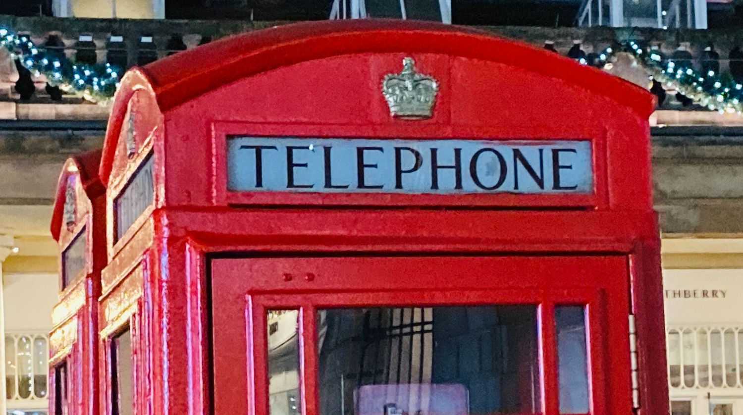 Row of classic British red telephone boxes lined up along a street.