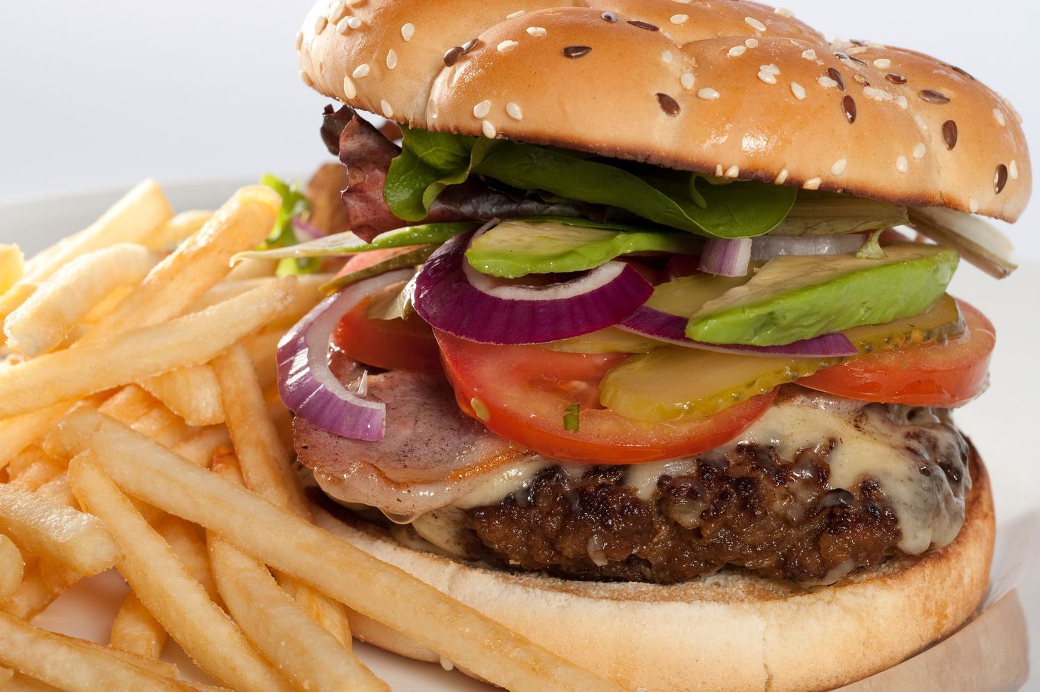 Juicy burger with melted cheese, fresh veggies, and bacon on sesame bun served with golden crispy french fries.