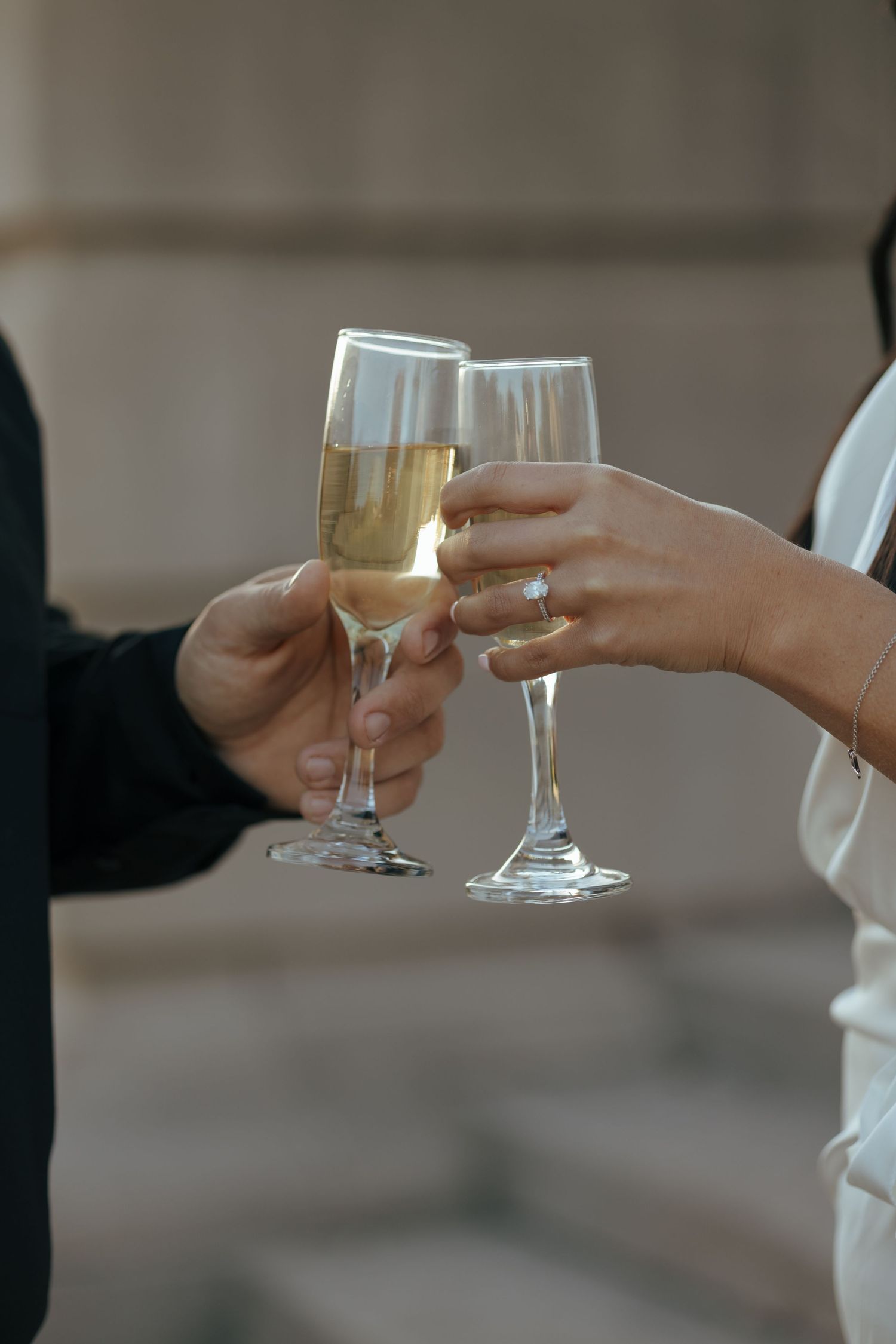 Two hands clinking champagne flutes in a celebratory wedding toast.