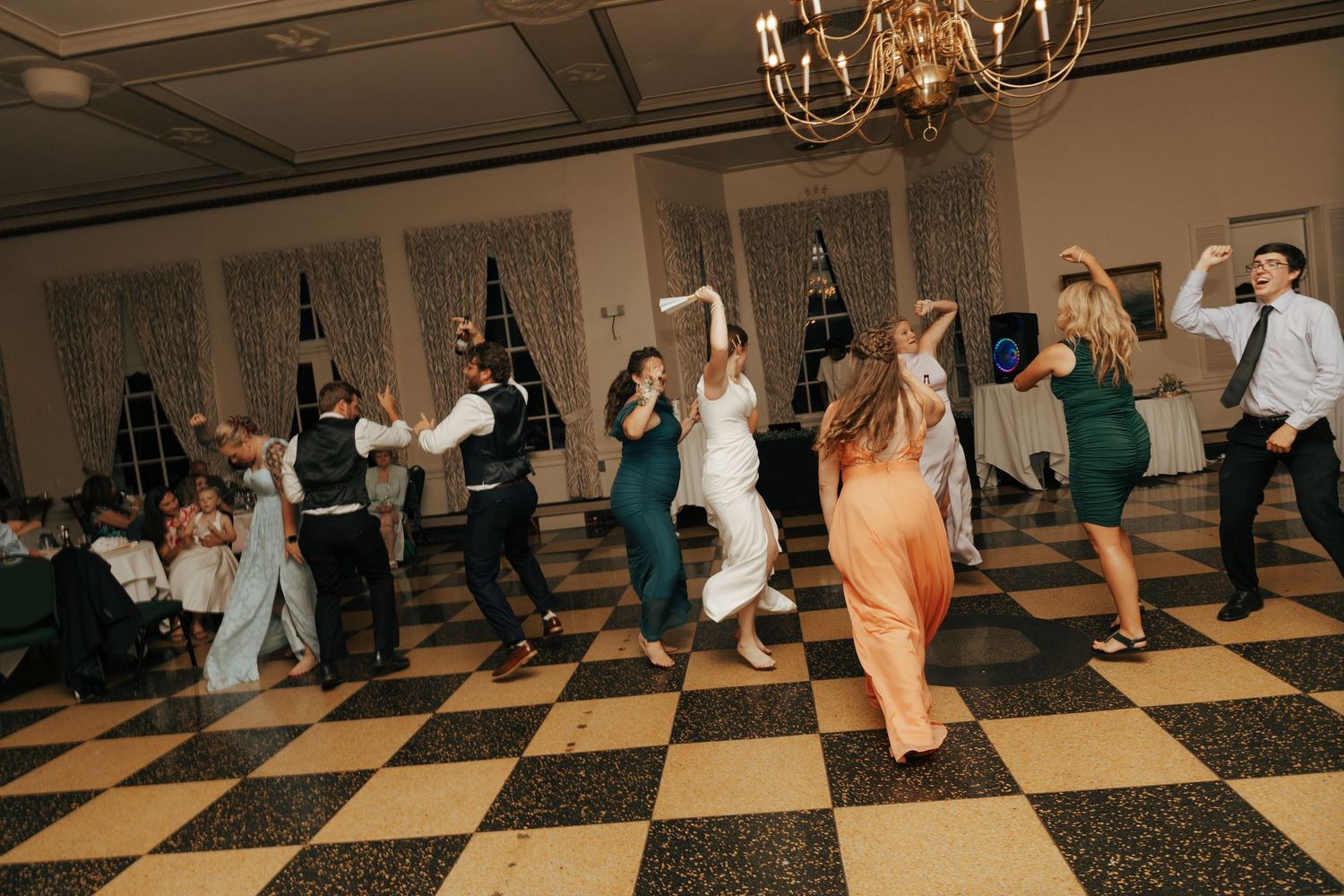 Lively wedding reception dance floor with guests in formal attire dancing together.