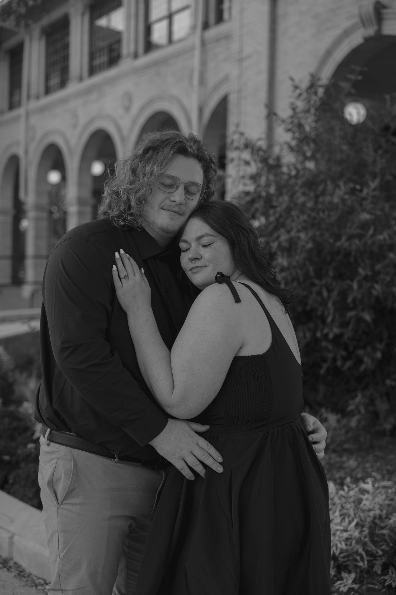 Black and white portrait of couple embracing tenderly outside a historic building.