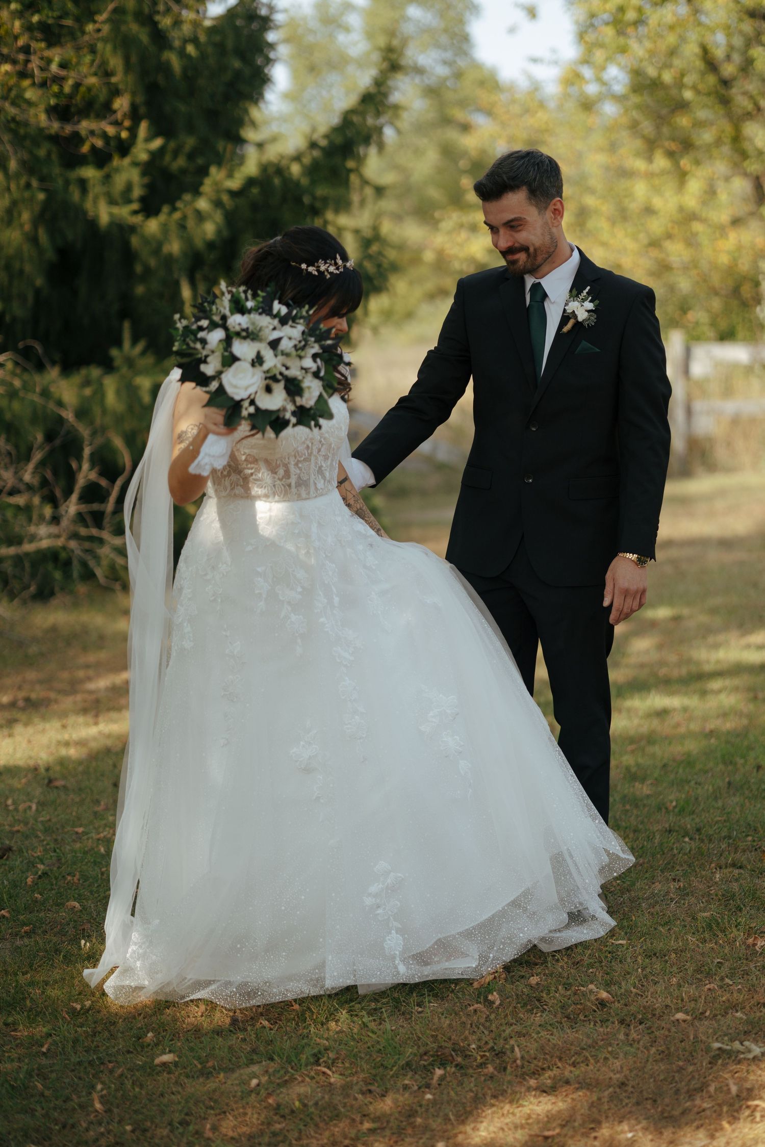 Smiling groom in a black suit holds his bride's hand as they have their first look.