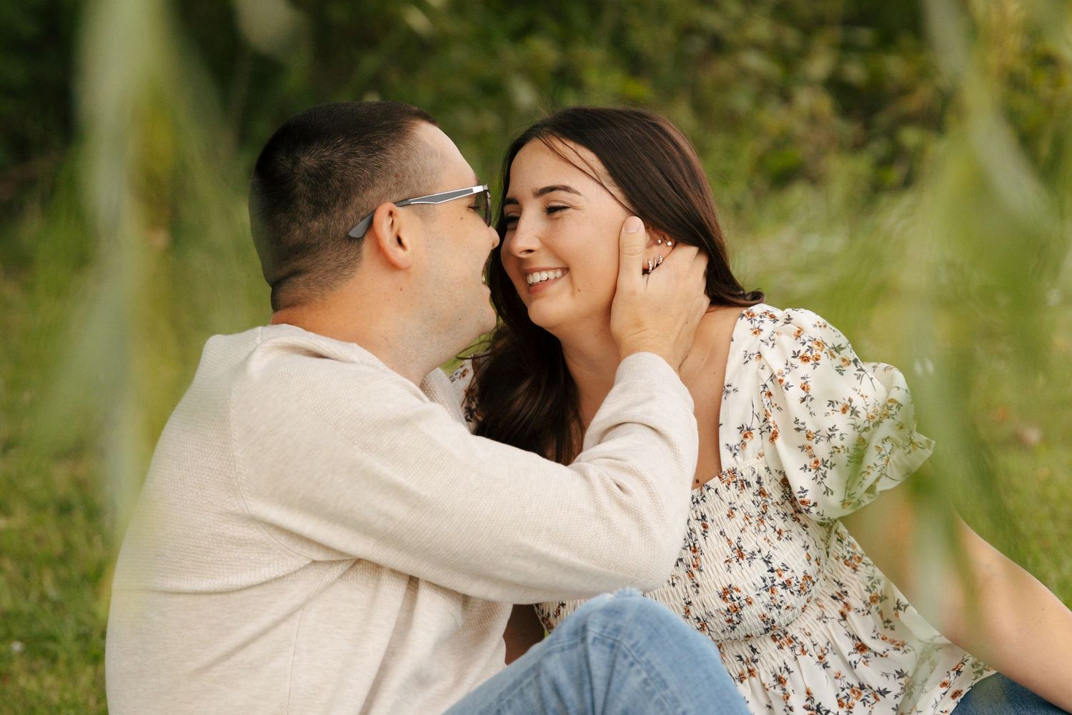 Happy couple sharing a tender moment outdoors, man touching womans face as she smiles joyfully.
