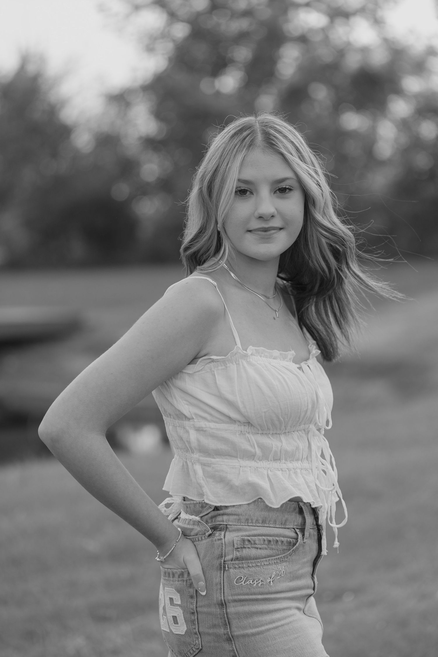 Black and white portrait of blonde teen girl in white crop top and Carhartt jeans posing outdoors at sunset.