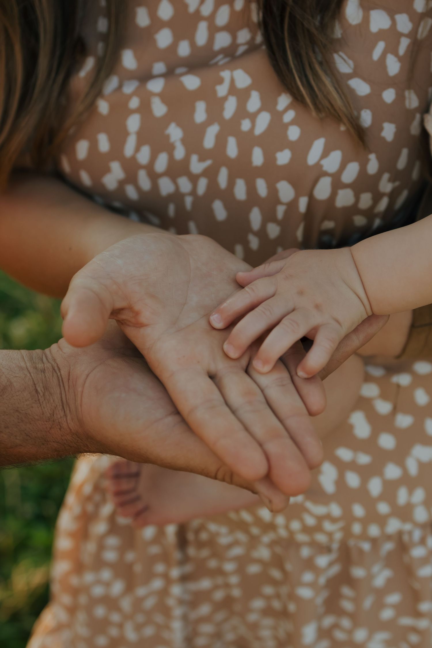 Close-up of three generations of hands stacked together, showing family connection outdoors.