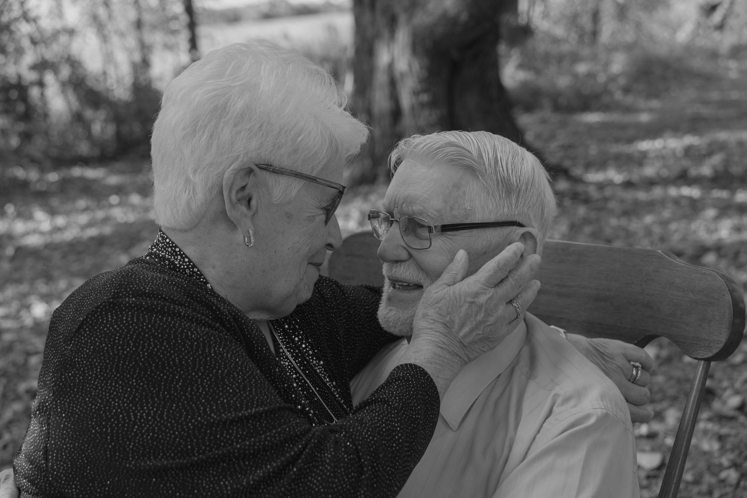 Black and white photo of elderly couple sharing an intimate moment, woman tenderly holds man's face.