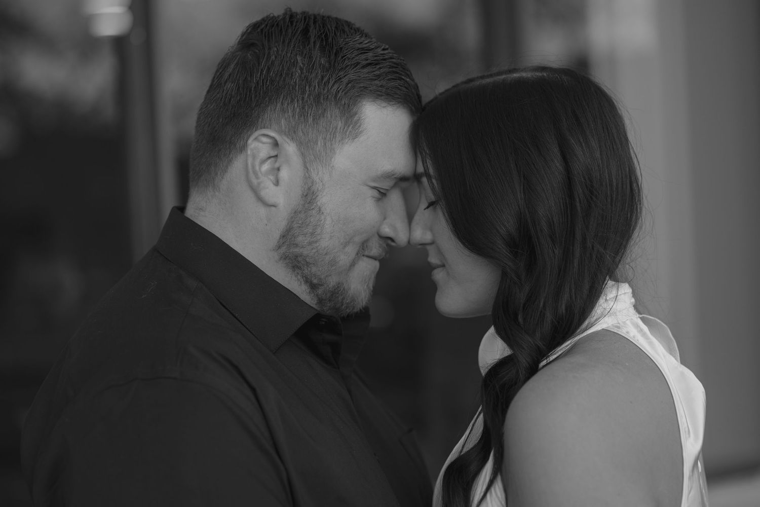 Black and white photo of a romantic couple sharing an intimate moment close together.