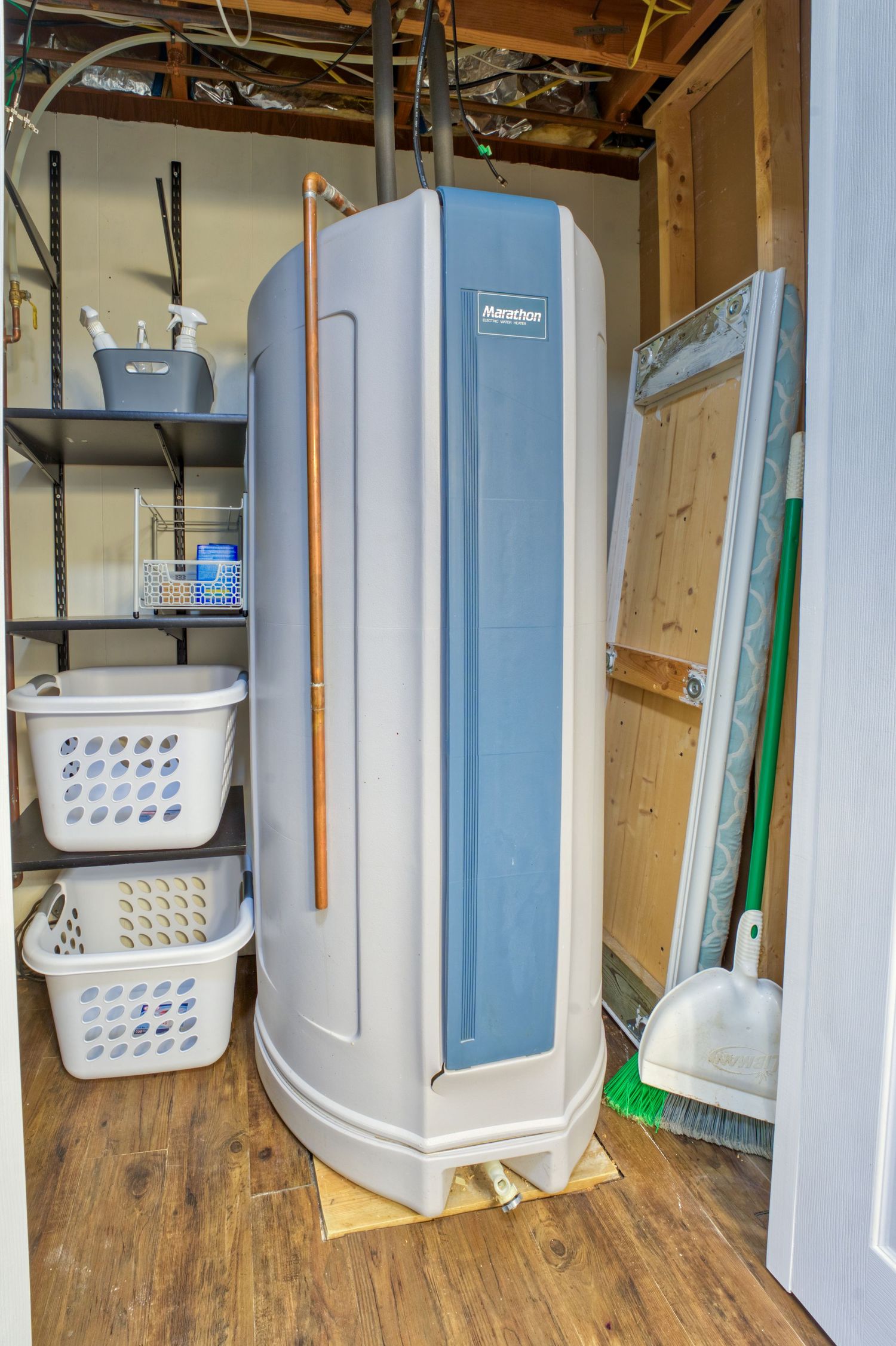 Marathon water heater in utility room with laundry baskets on shelving and cleaning supplies nearby.