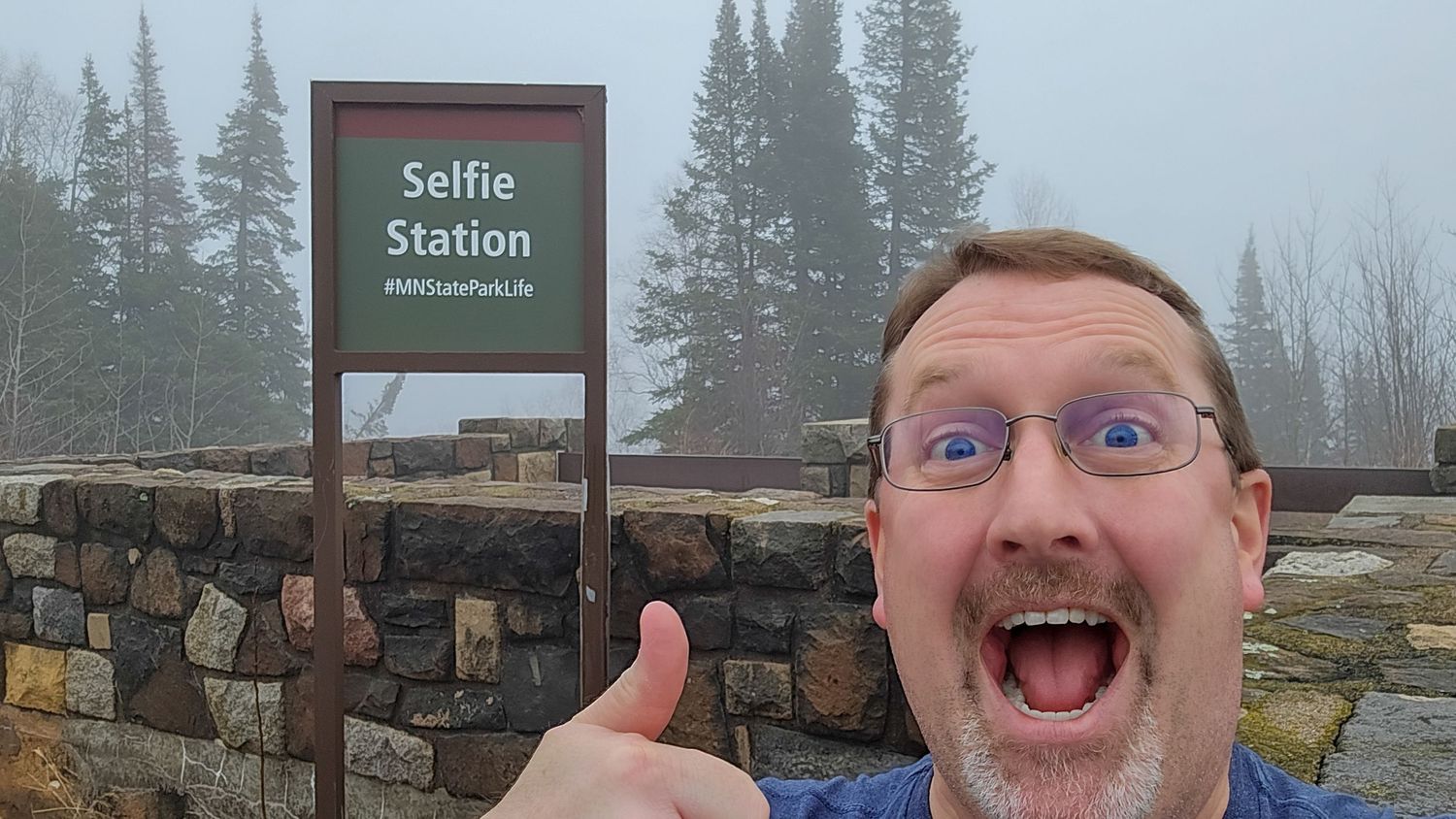 Winter landscape with selfie station sign and snow-covered trees.