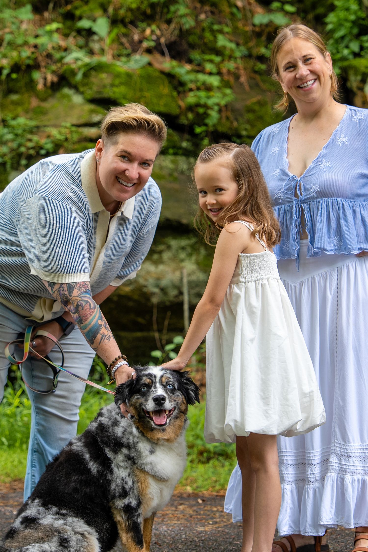 A family poses with their Australian Shepherd dog on a garden path.