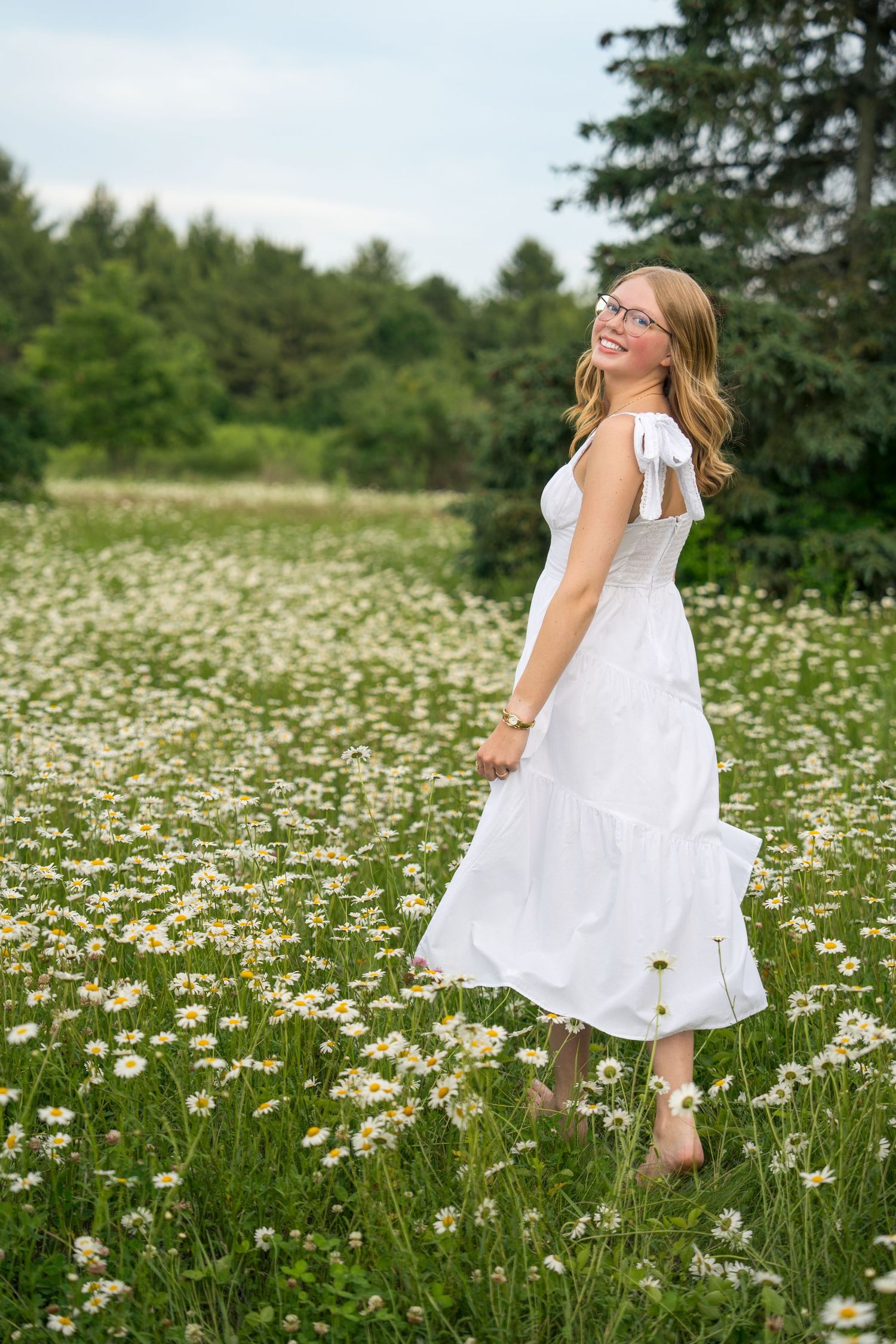 A child in a white dress dances and twirls through a sunny meadow filled with blooming daisies and wildflowers.
