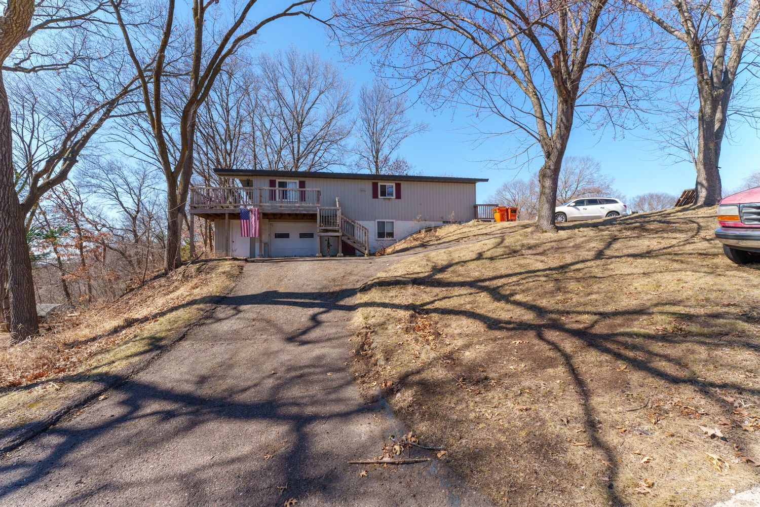 Panoramic view of a sloped yard with bare trees and residential buildings in winter.