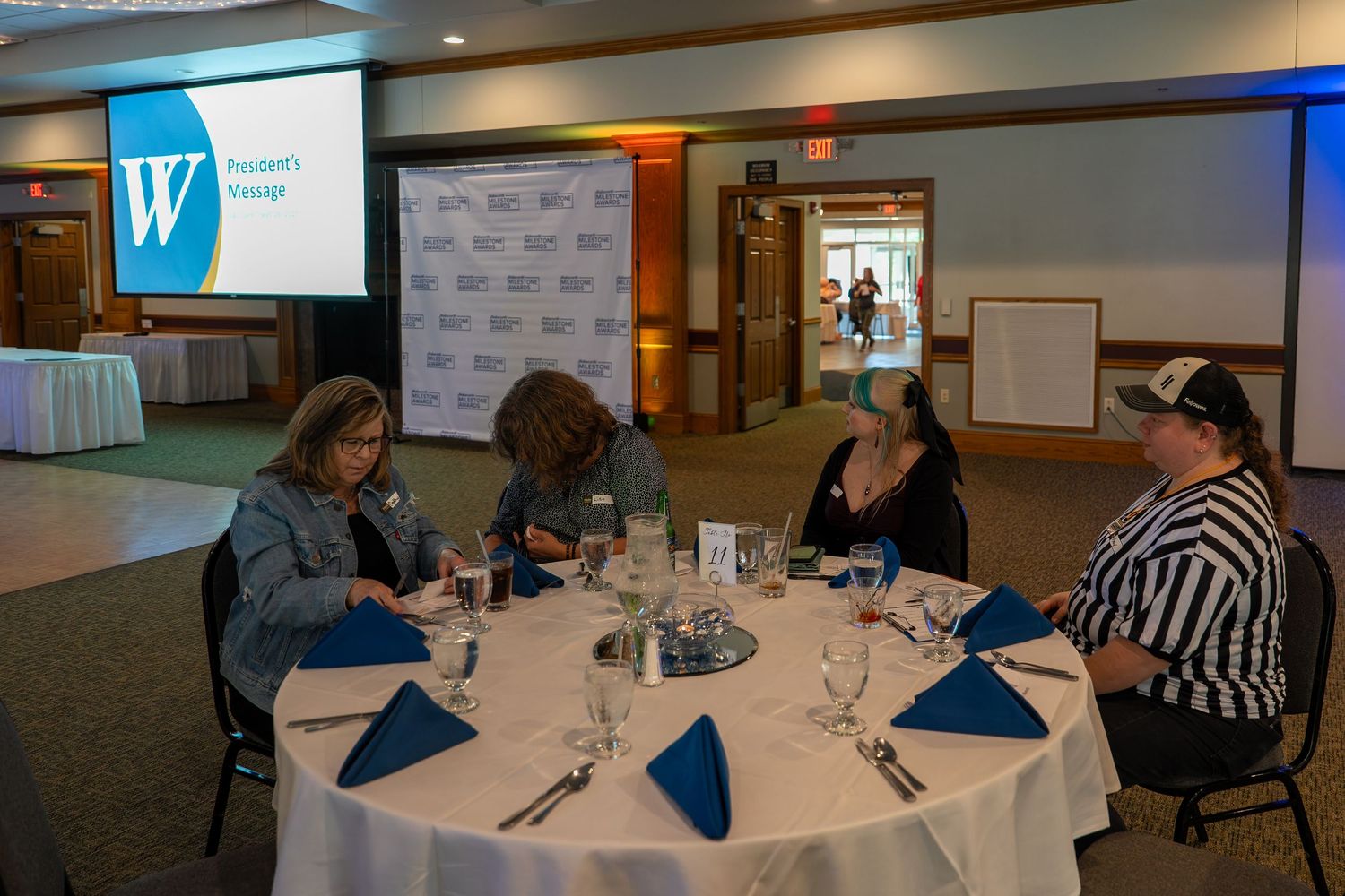 Business professionals gathered around round tables in a conference room setting for a workshop or meeting.