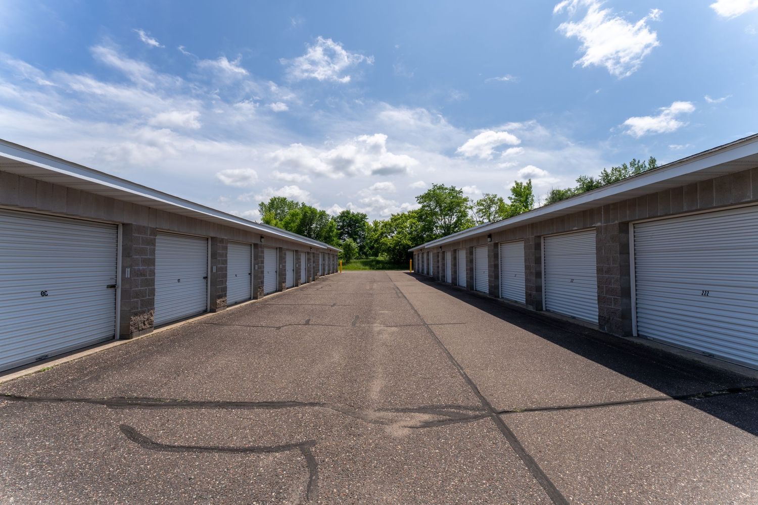 Brown asphalt shingle roofing on residential buildings with white siding under a partly cloudy blue sky.