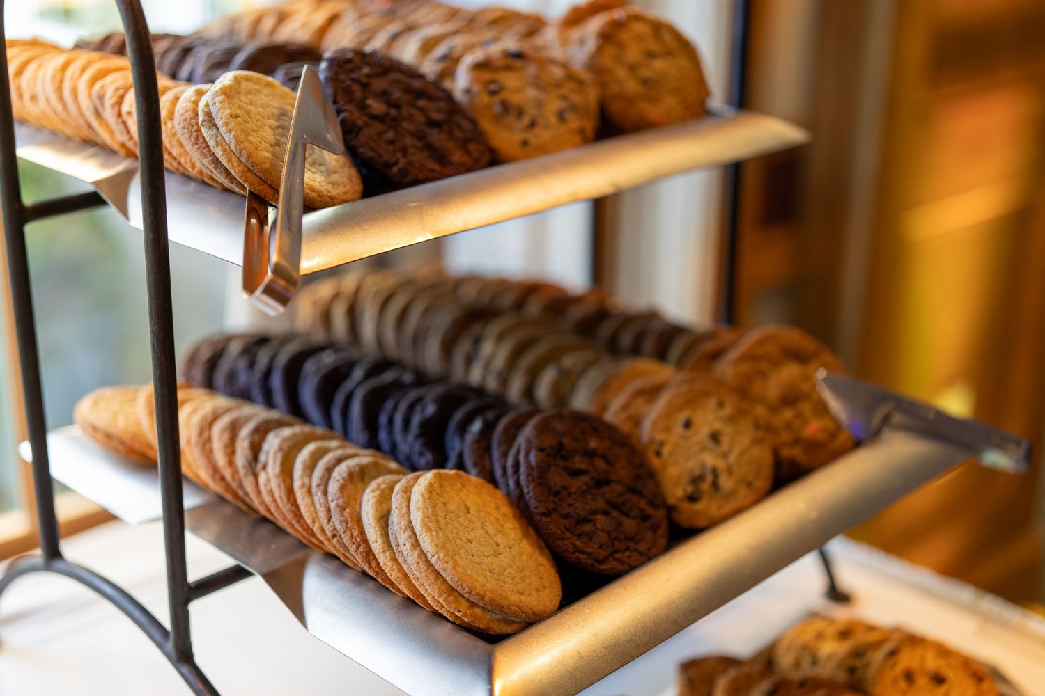 Fresh baked cookies and pastries displayed on wooden shelves in a bakery case.