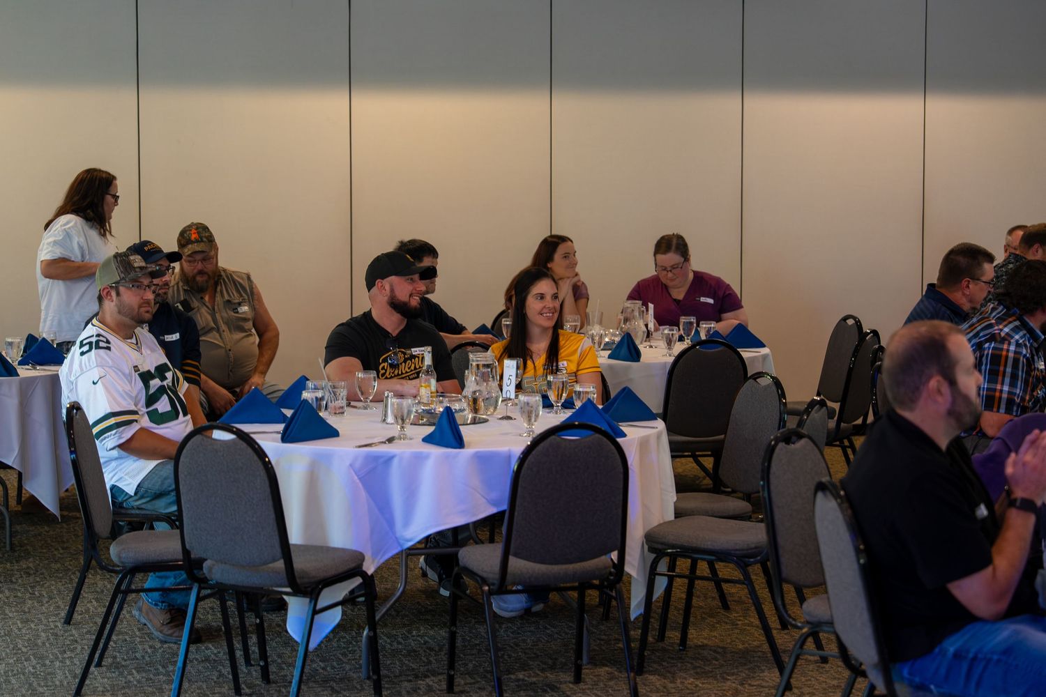 Conference room setup with multiple round tables and chairs arranged for a business event or seminar.
