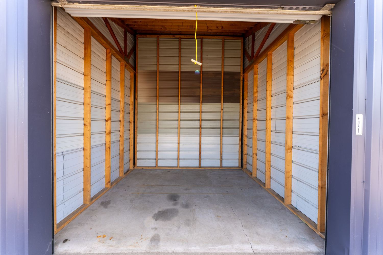 Interior view of empty storage units with orange safety railings and concrete floors in a well-lit facility.