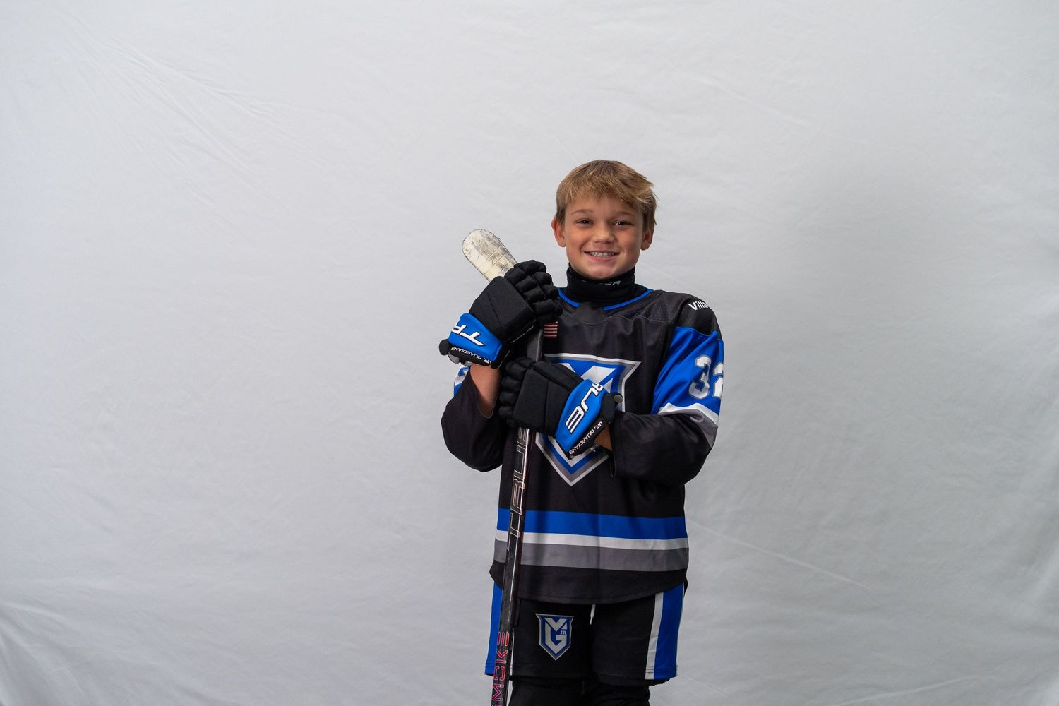 Young sports fan in a Carolina Panthers jersey gives a thumbs up while posing against a gray background.