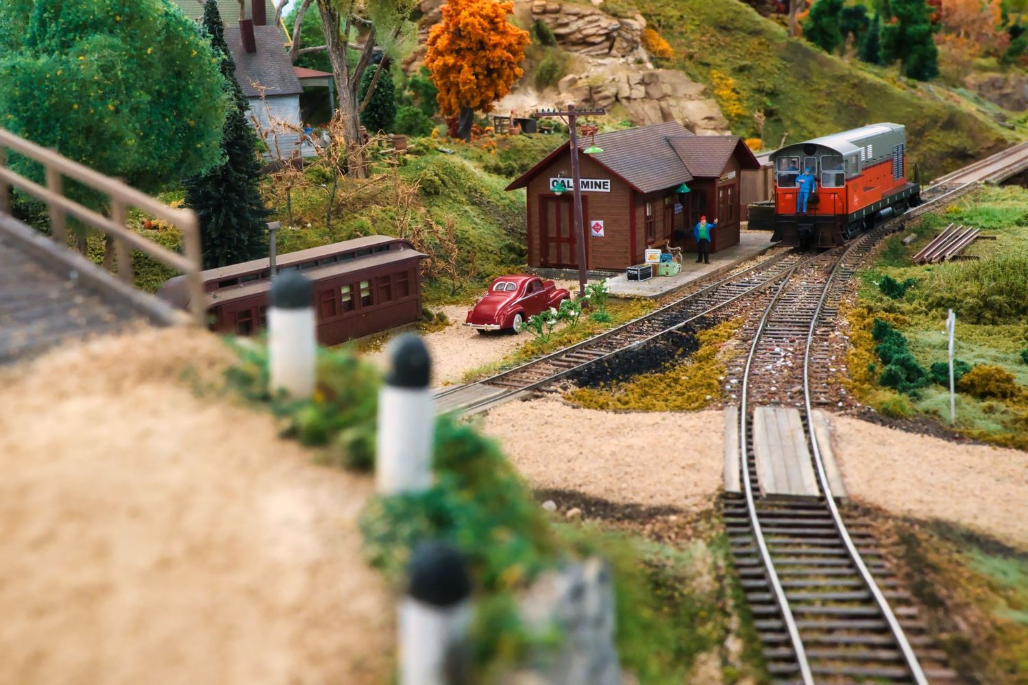 Model train layout showing detailed mountain scenery with tracks winding through a miniature forest landscape.