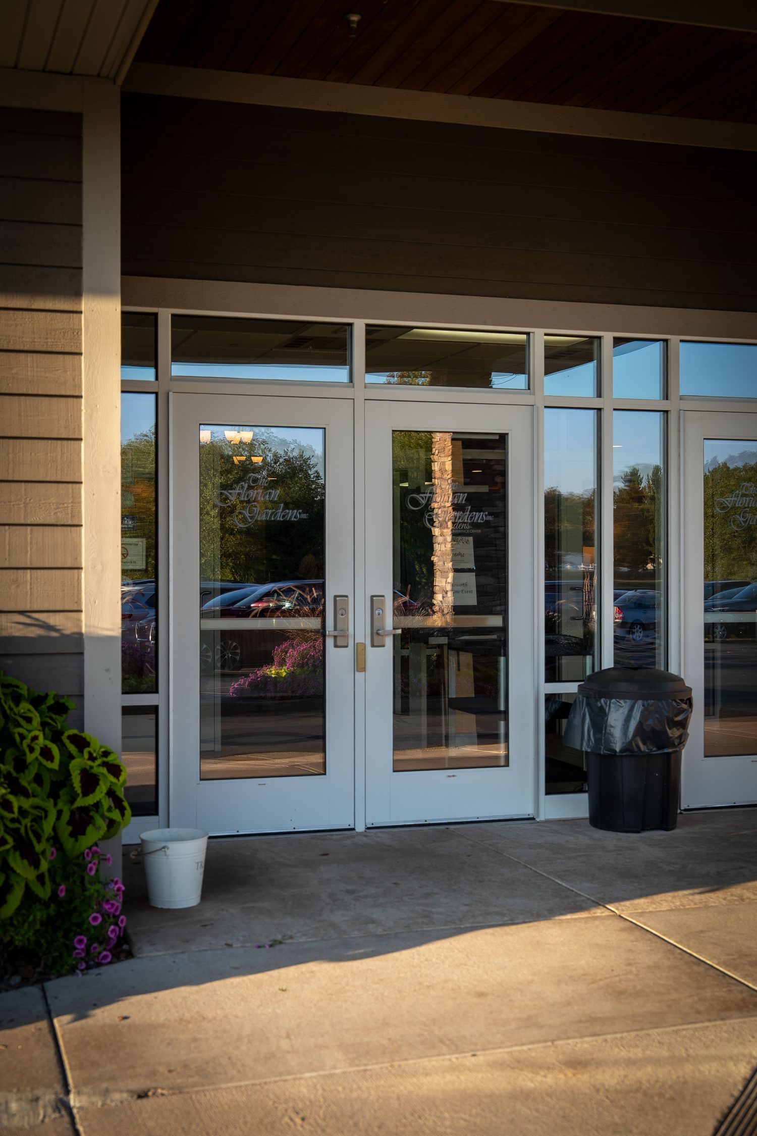 Modern commercial building entrance with glass double doors and covered walkway in daytime lighting.