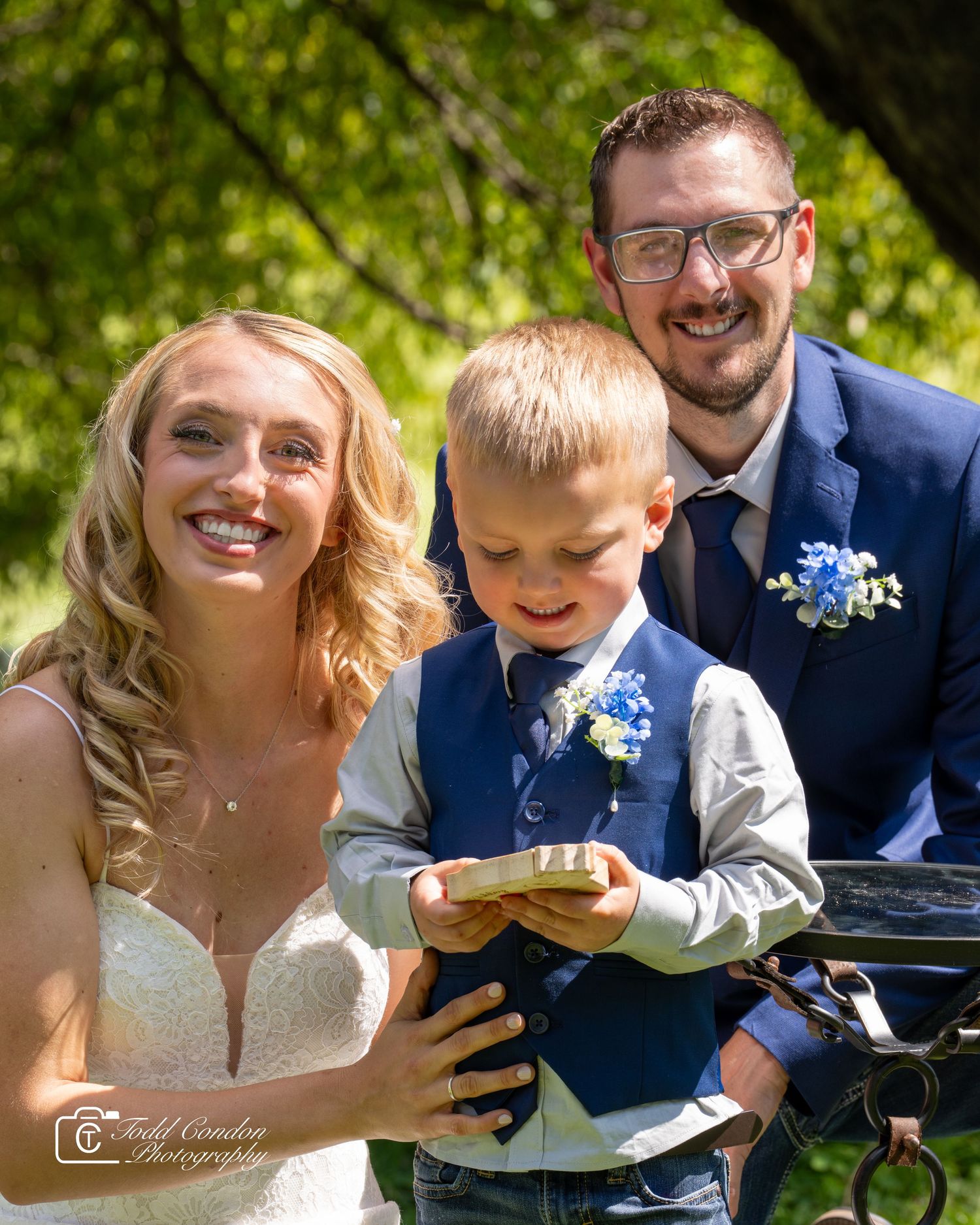 A couple shares a joyful moment outdoors during their wedding celebration with natural greenery in the background.