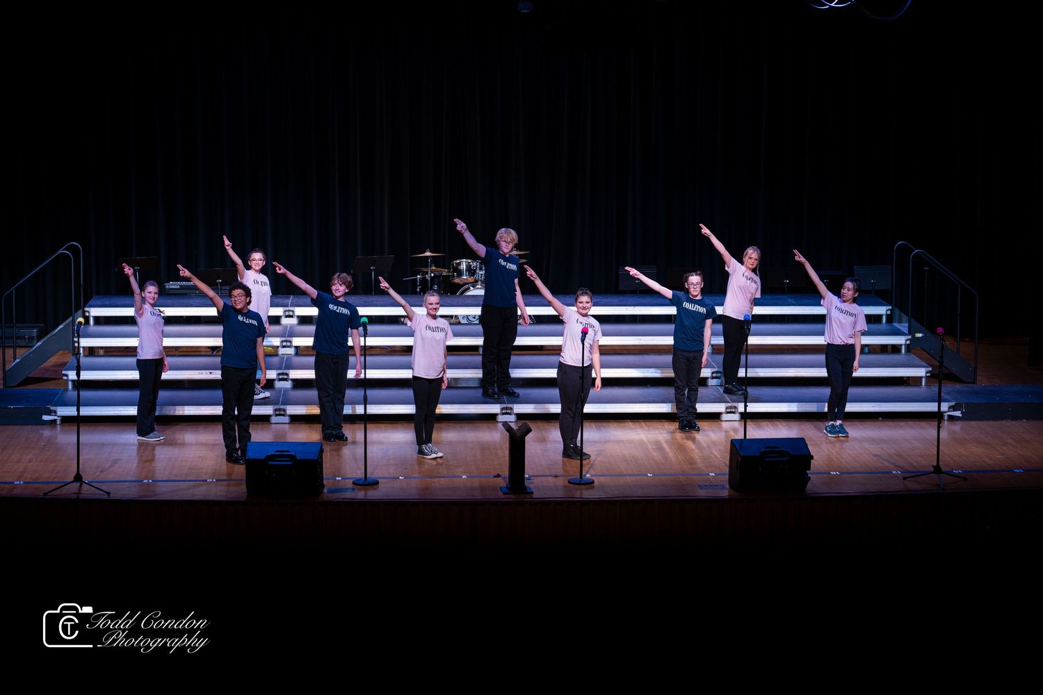 Silhouetted dancers perform a synchronized routine on a dark stage with dramatic lighting effects.