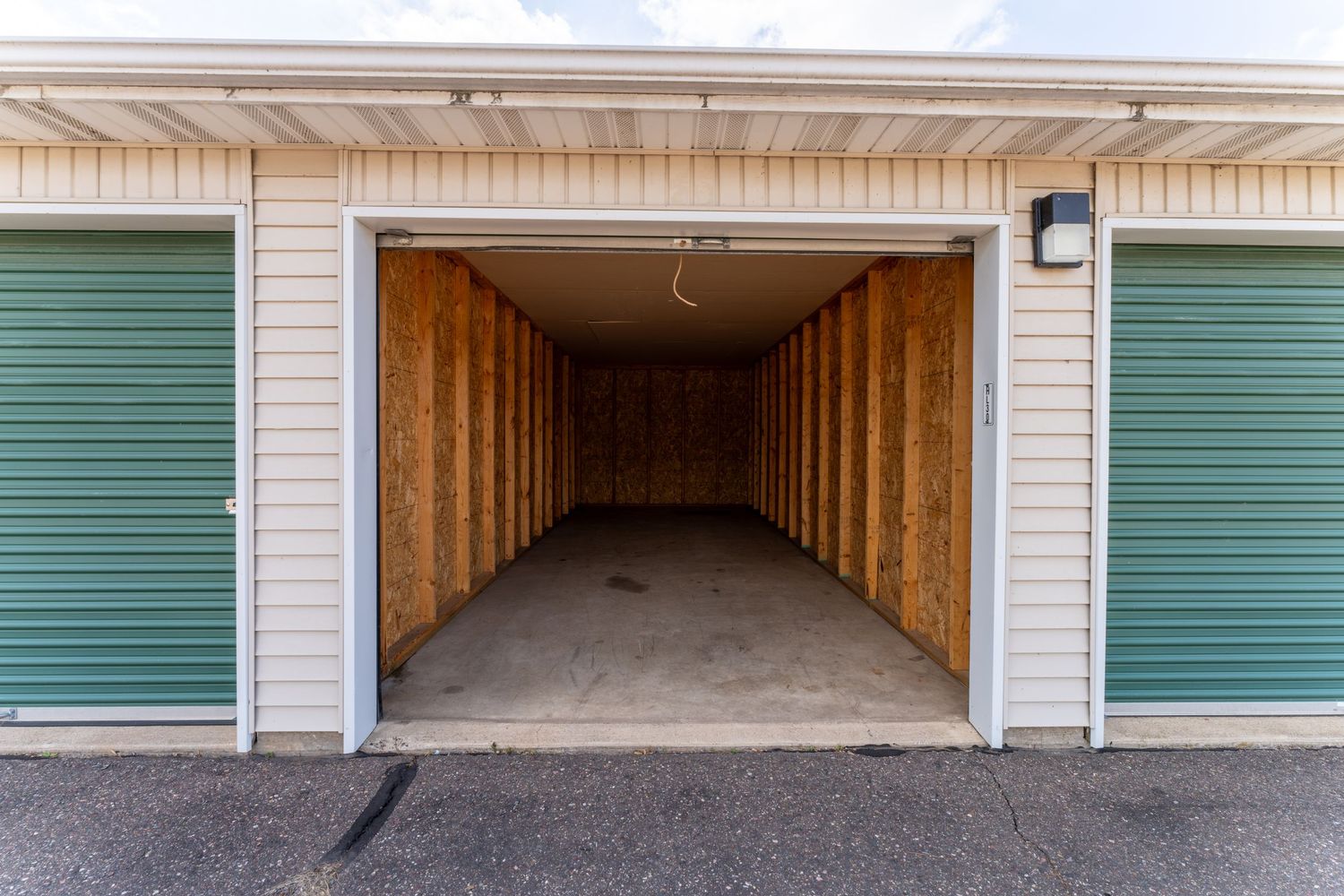 A row of storage units with teal colored doors and white trim extends down a long hallway.