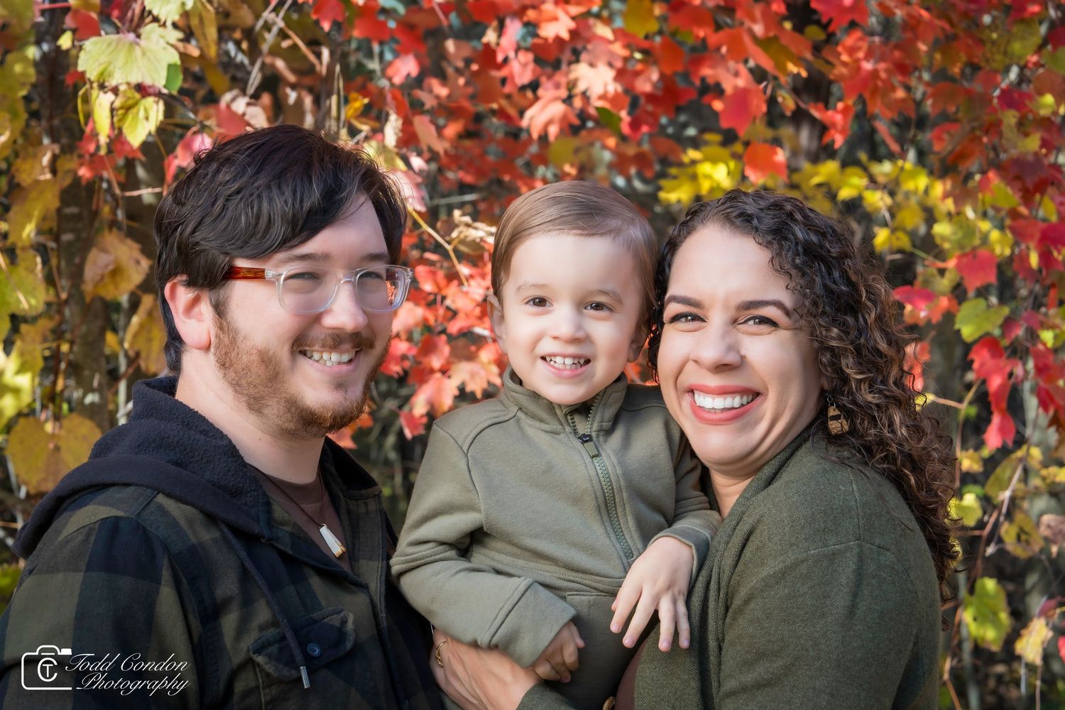 Family portrait with colorful fall foliage background creating warm autumn atmosphere.