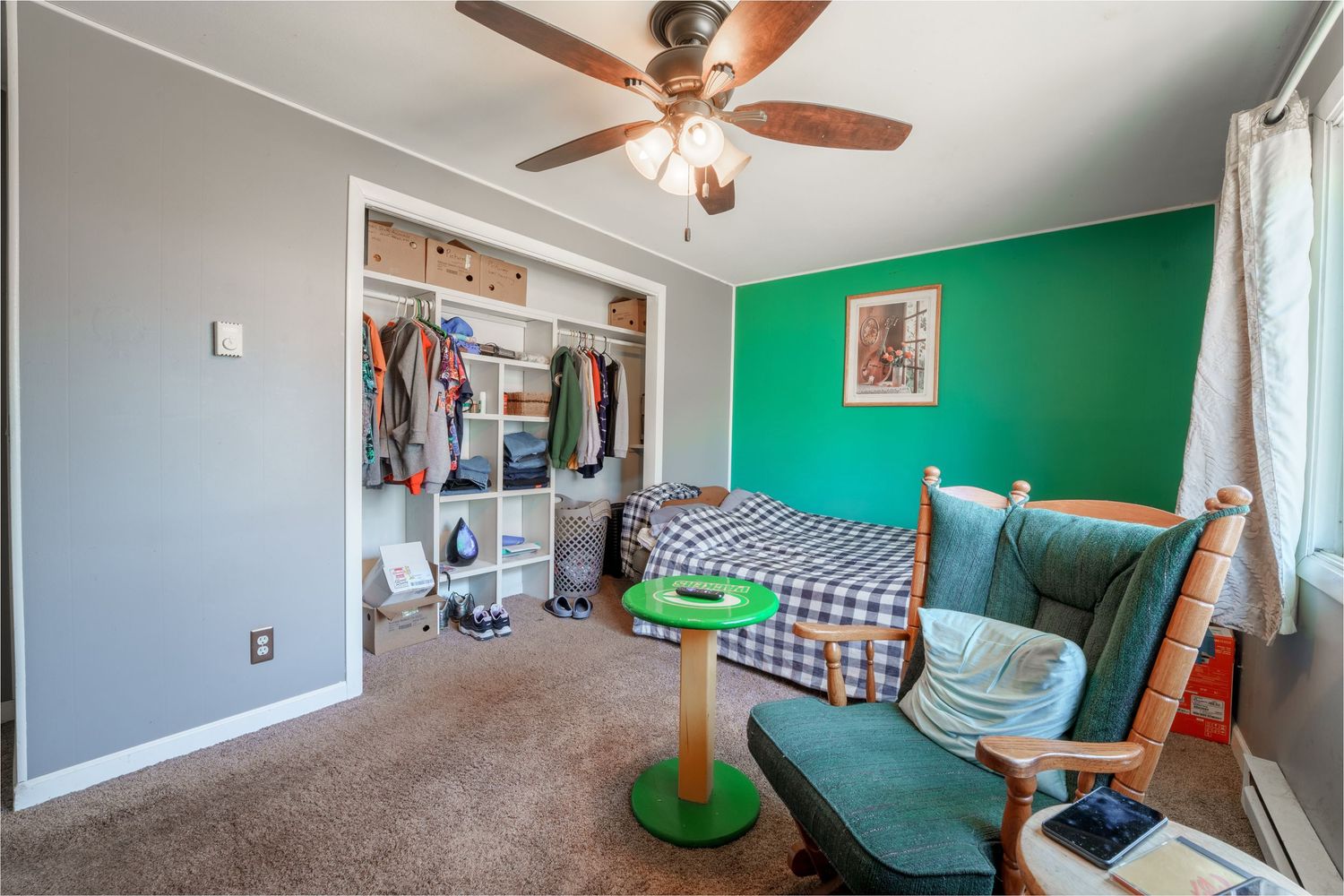 Panoramic view of a modern bedroom with ceiling fan, green accent wall, and natural light streaming through windows.